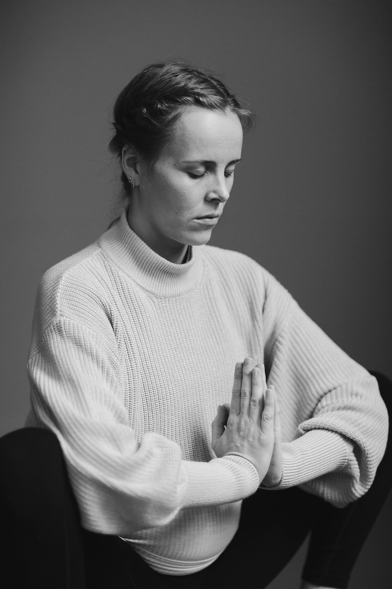 Portrett av kvinne med lukkede øyne og samlede hender i yogapositur.