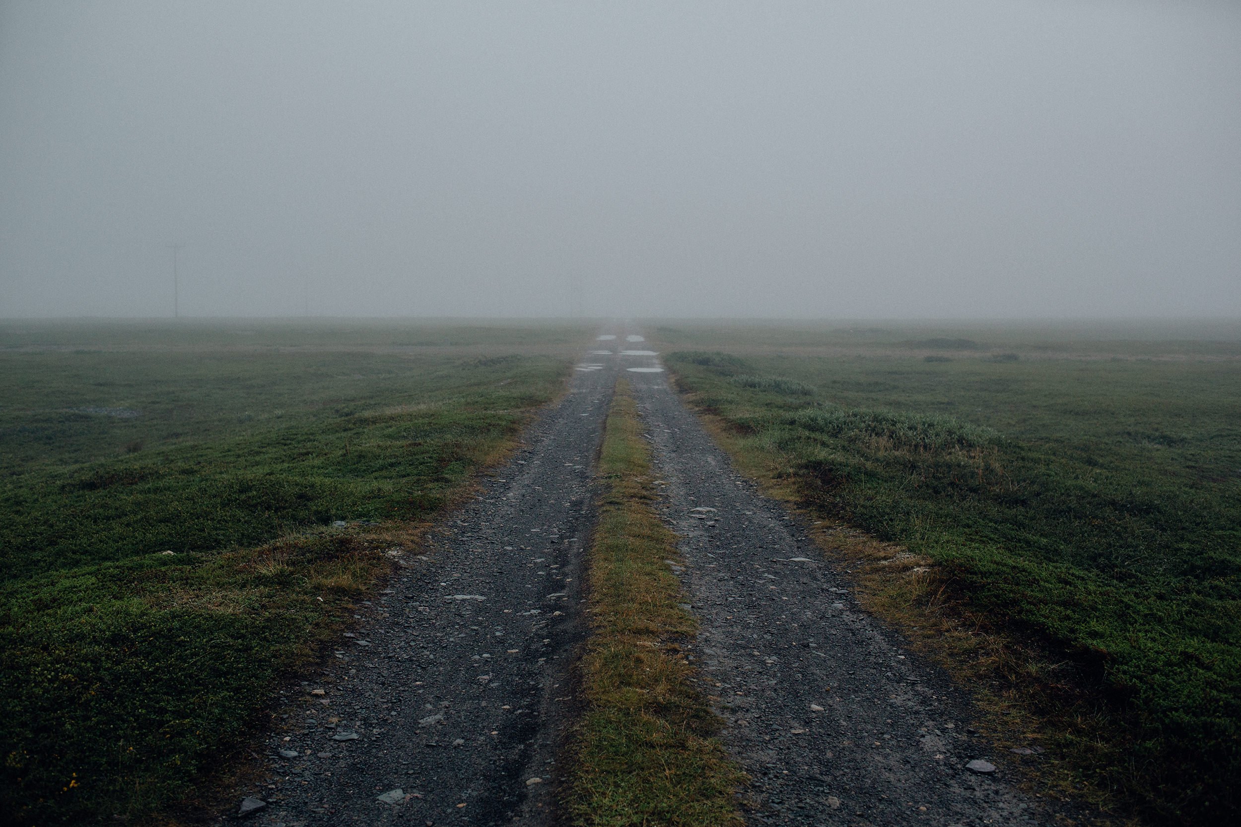 Sliten grusvei som går rett fram og forsvinner i tåka ved Varanger.