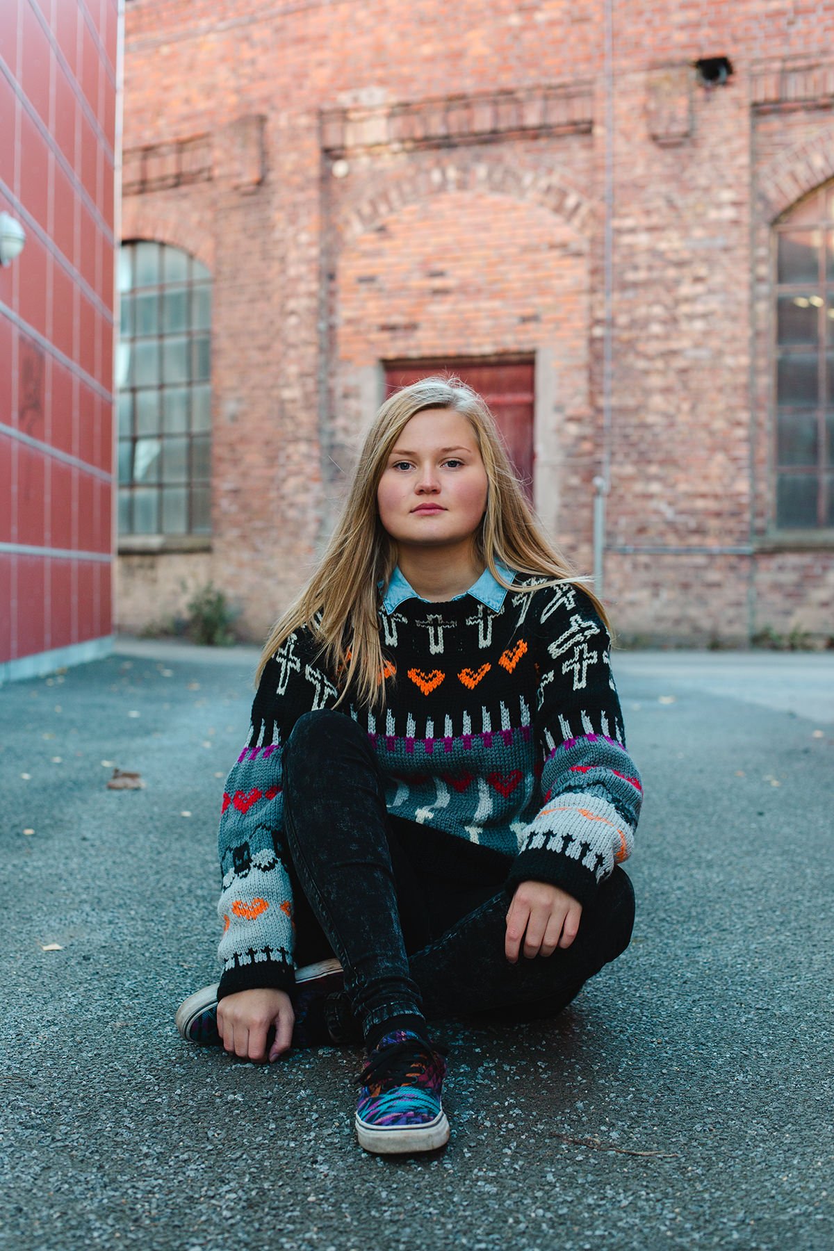 Konfirmantfotografering av jente som sitter på bakken.