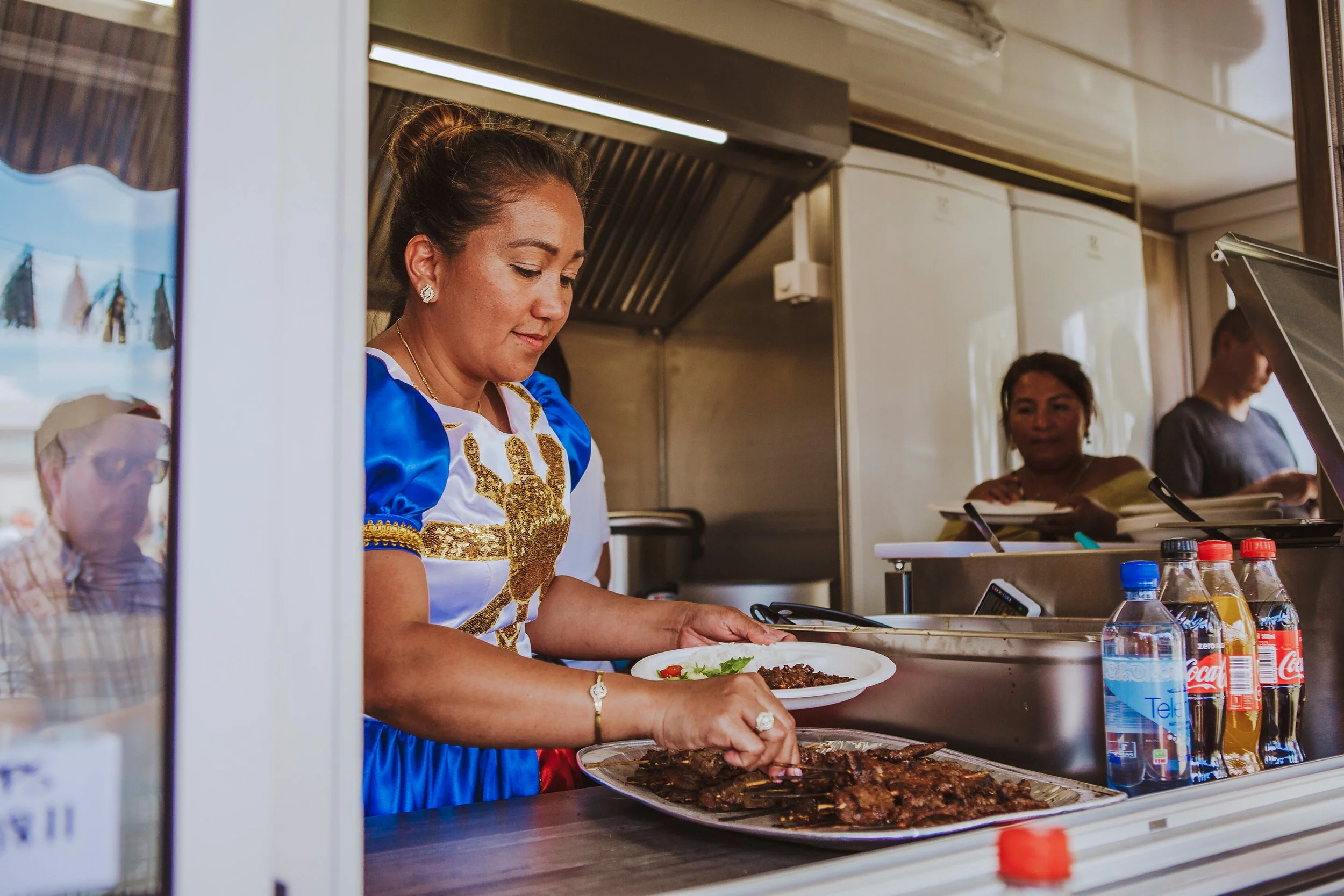 Stoppested Verden internasjonal barnefestival. Kvinne serverer mat fra en foodtruck.