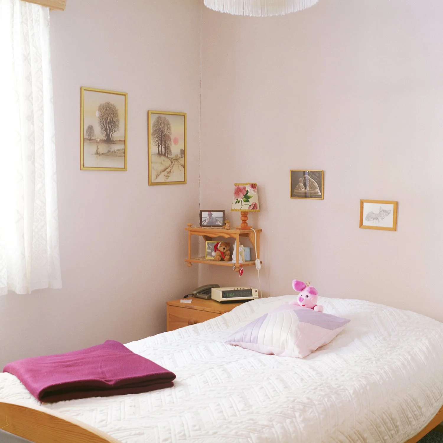 Interiør. Soverom med rosa vegger og oppredd seng med teppe, pute og bamse.