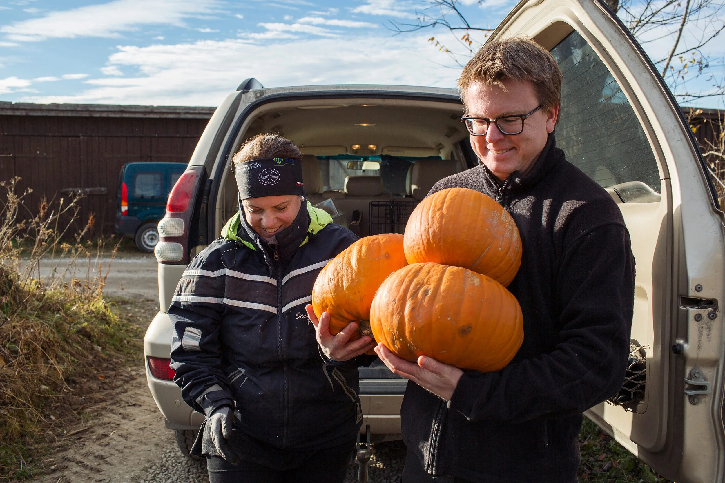 Kvinne og mann bærer gresskar ut fra bilen.