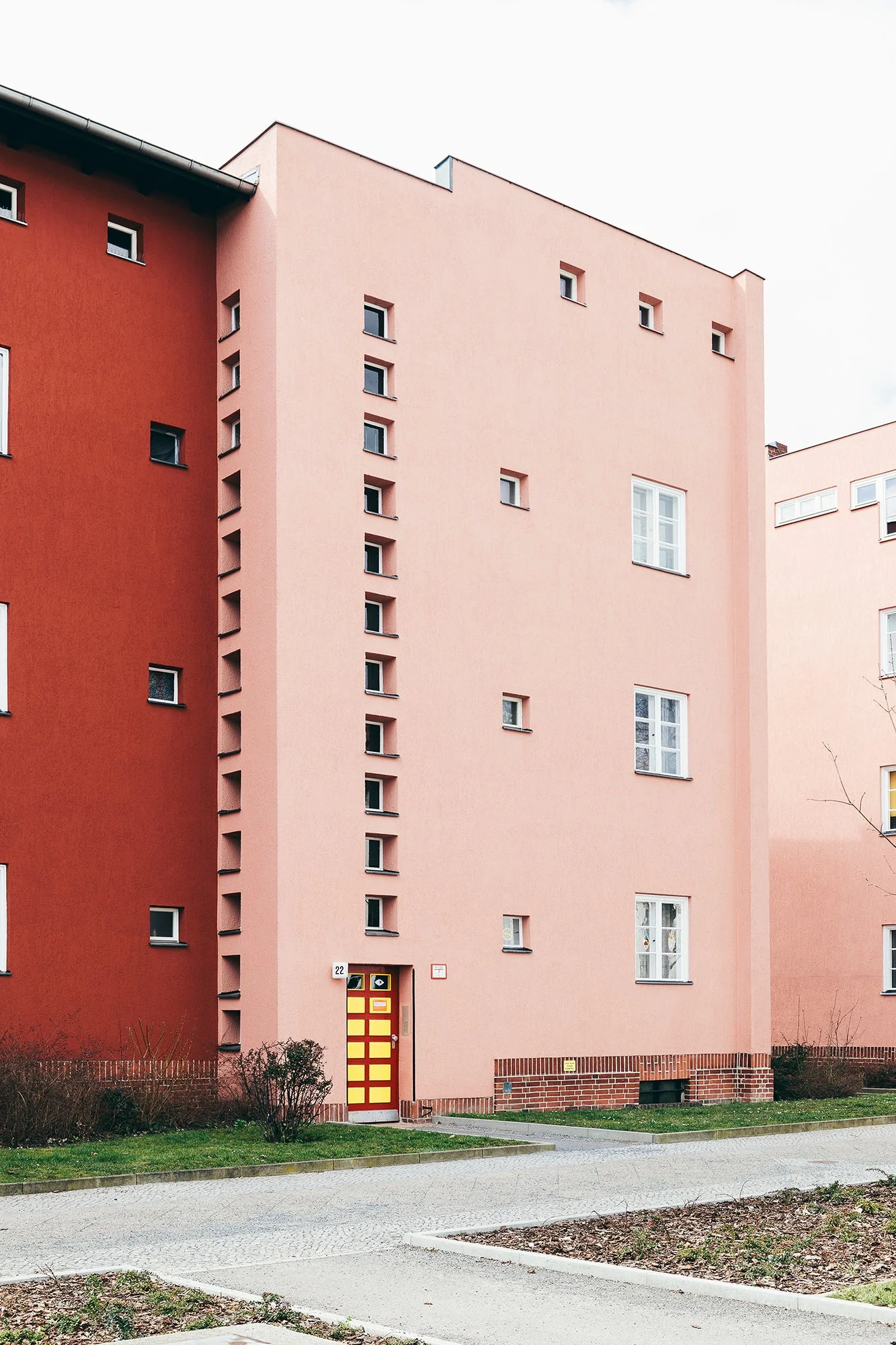 Rosa og rødt murbygg med gul dør i boligfelt i Berlin, tegnet av arkitekt Bruno Taut.