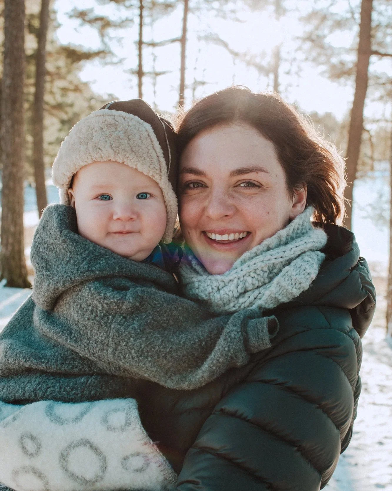 Familiefotografering utendørs på vinteren. Mor holder baby på et halvt år.