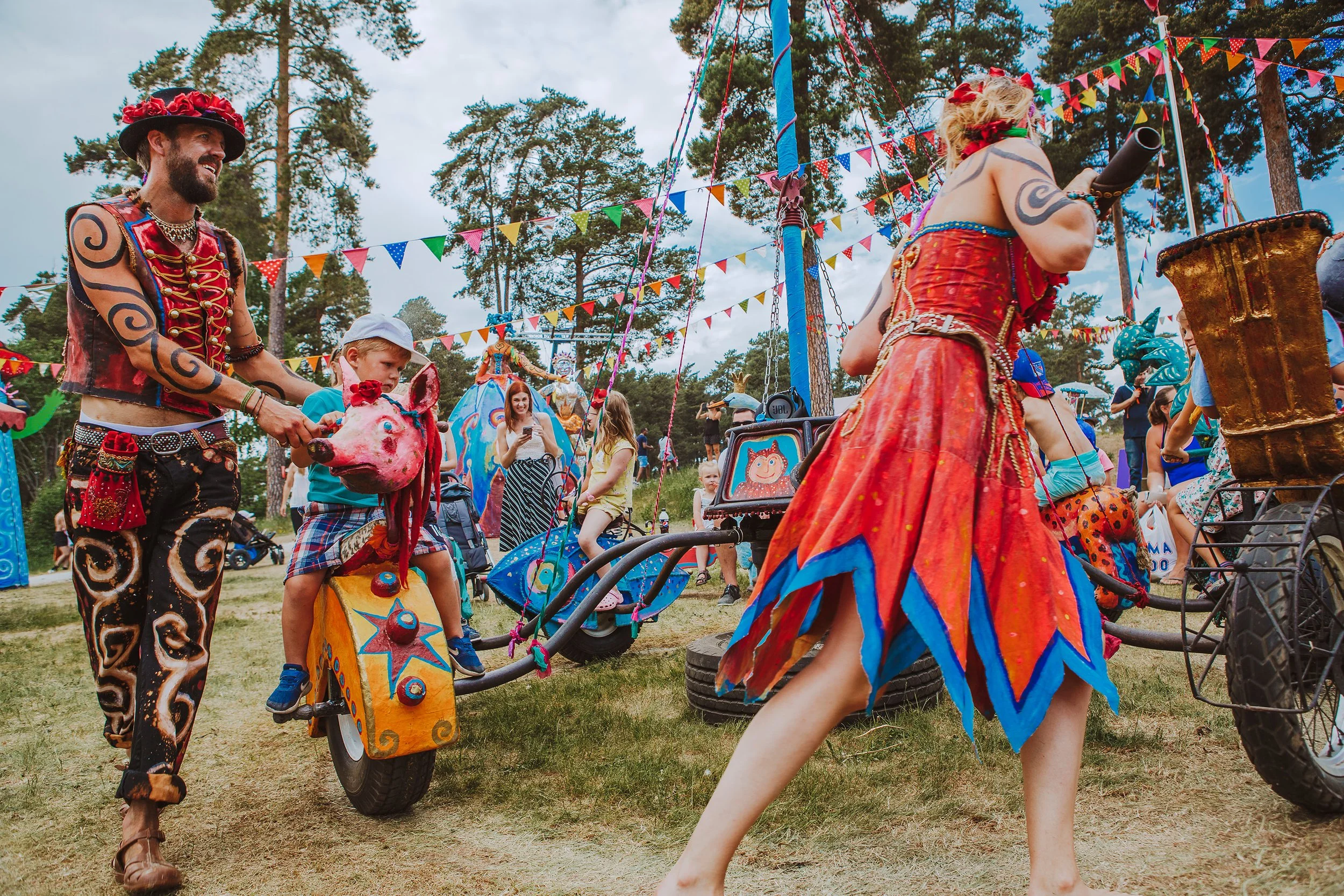 Stoppested Verden internasjonal barnefestival. Artister i fargerike drakter opererer en manuell karusell.