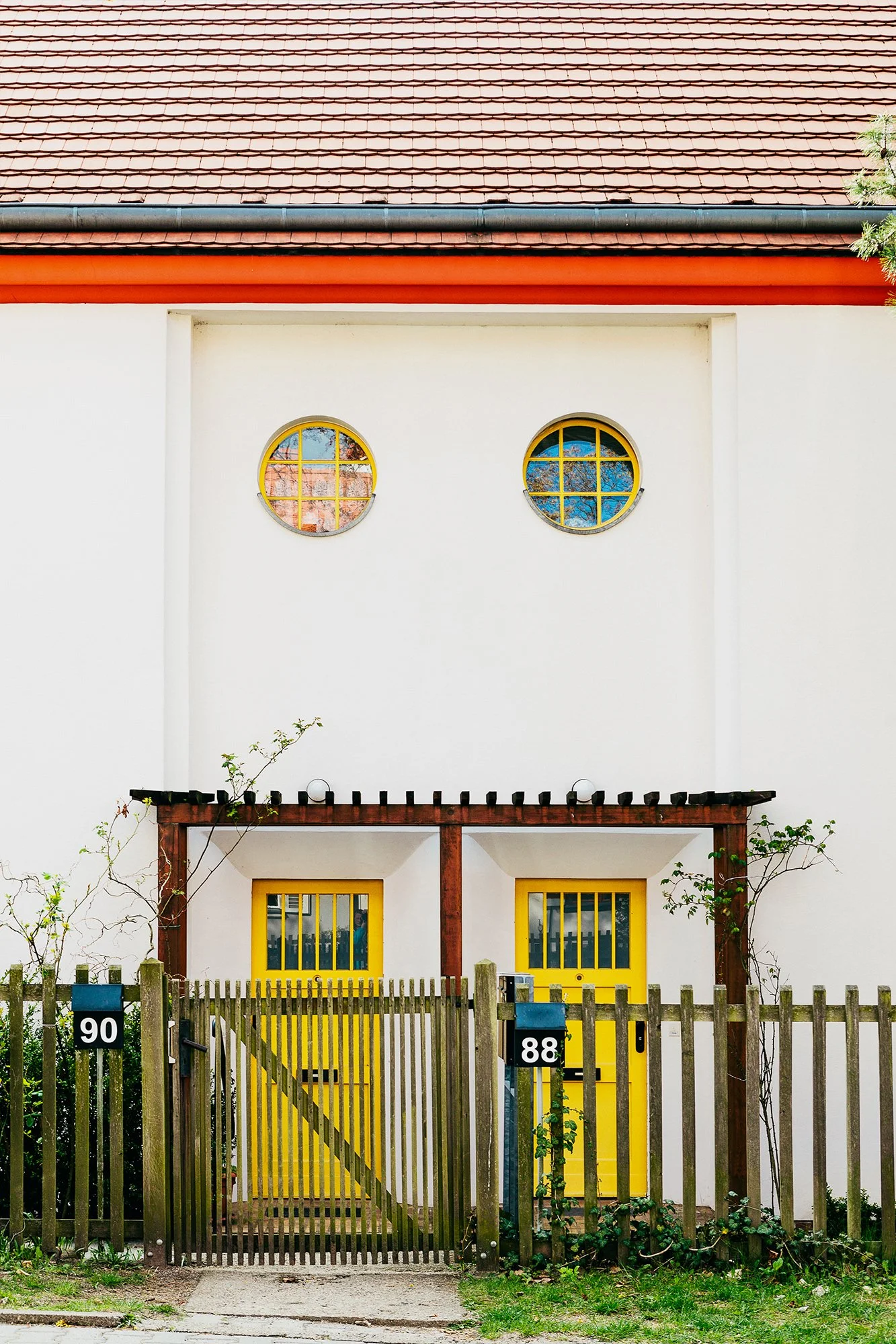 Boligfelt i Gartenstadt Falkenberg i Berlin, tegnet av arkitekt Bruno Taut. Hvitt murbygg med to knall gule inngangsdører og runde vinduer.