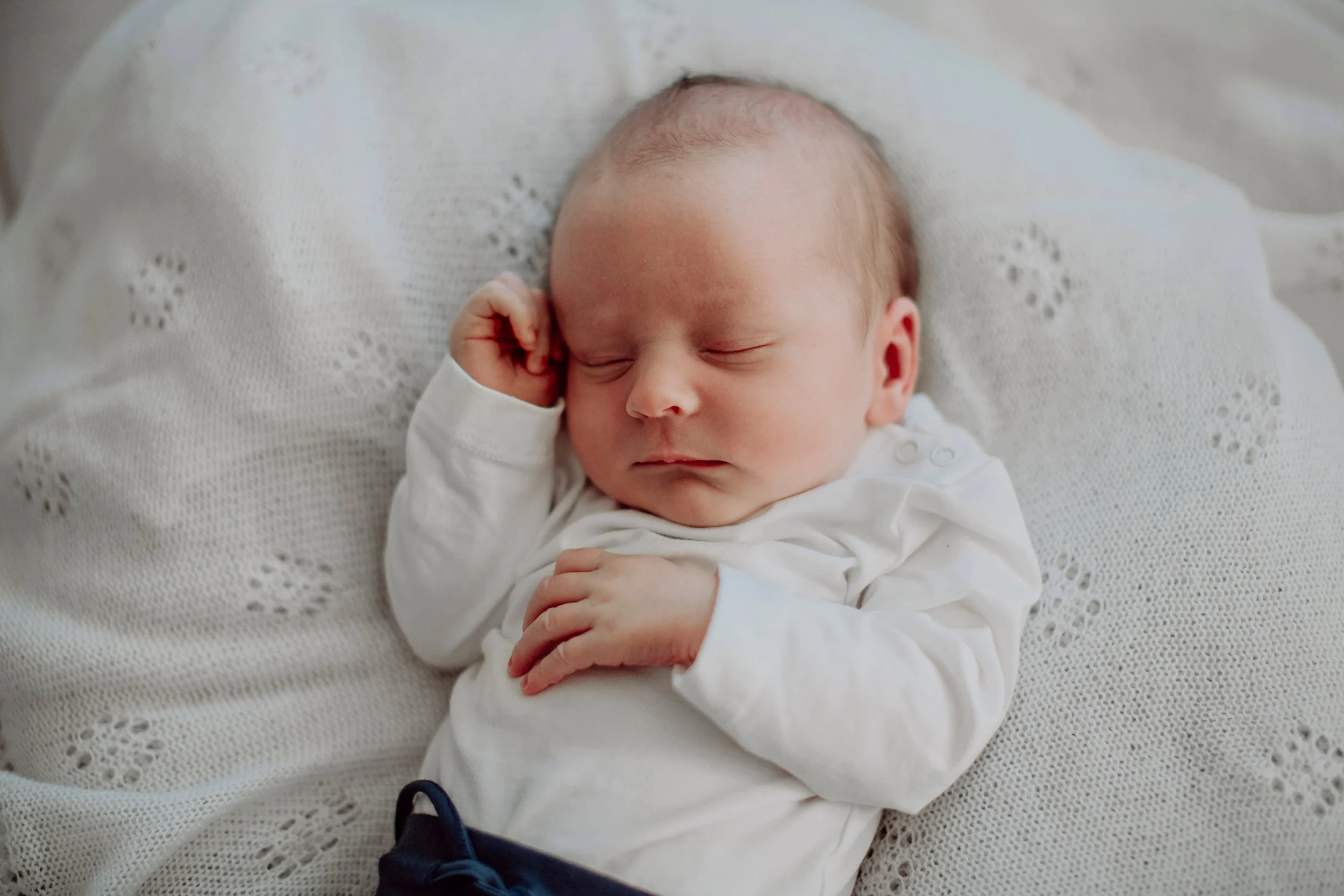 Nyfødtfotografering av sovende baby på teppe