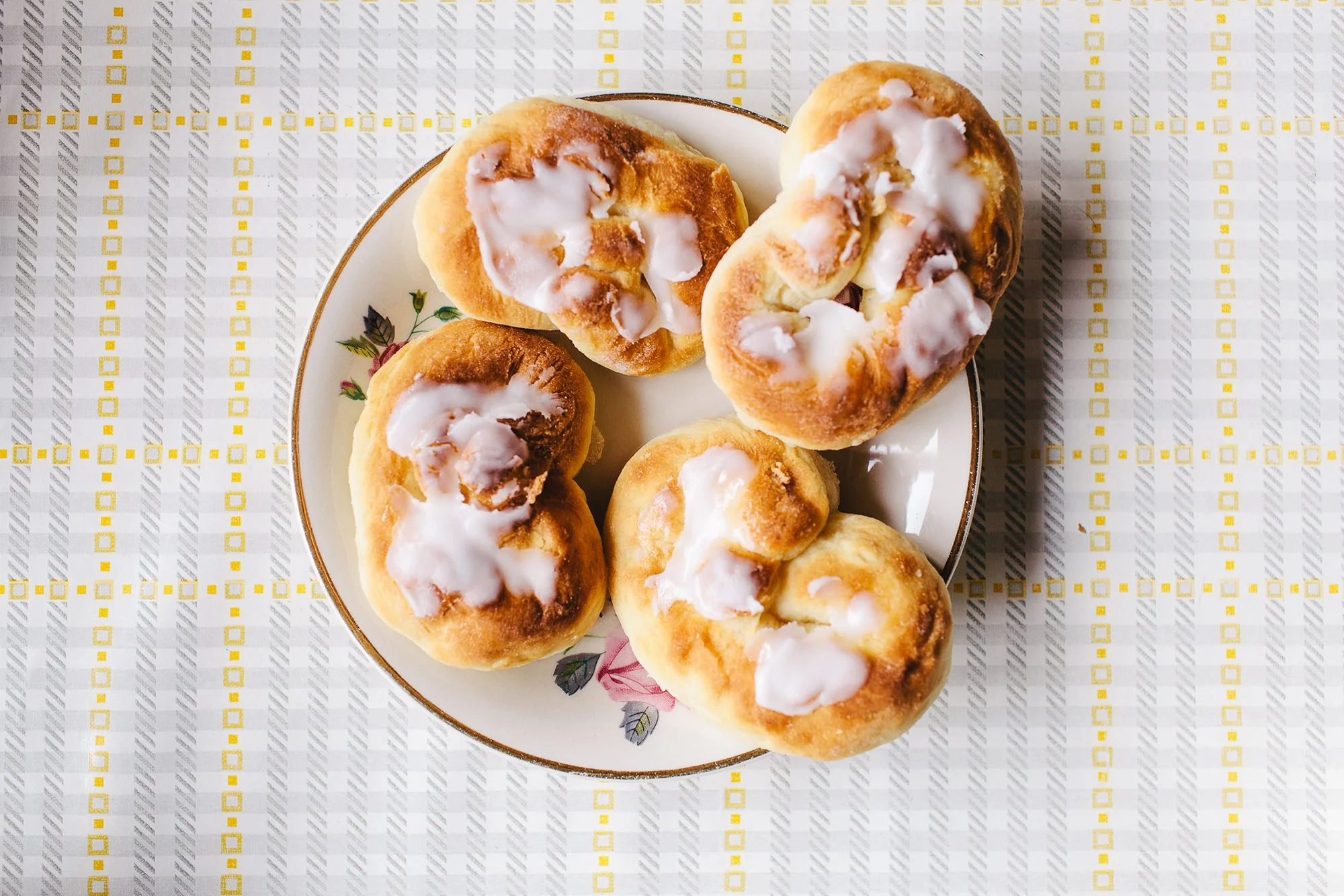 Kringler med melis på tallerken fotografert i fugleperspektiv.