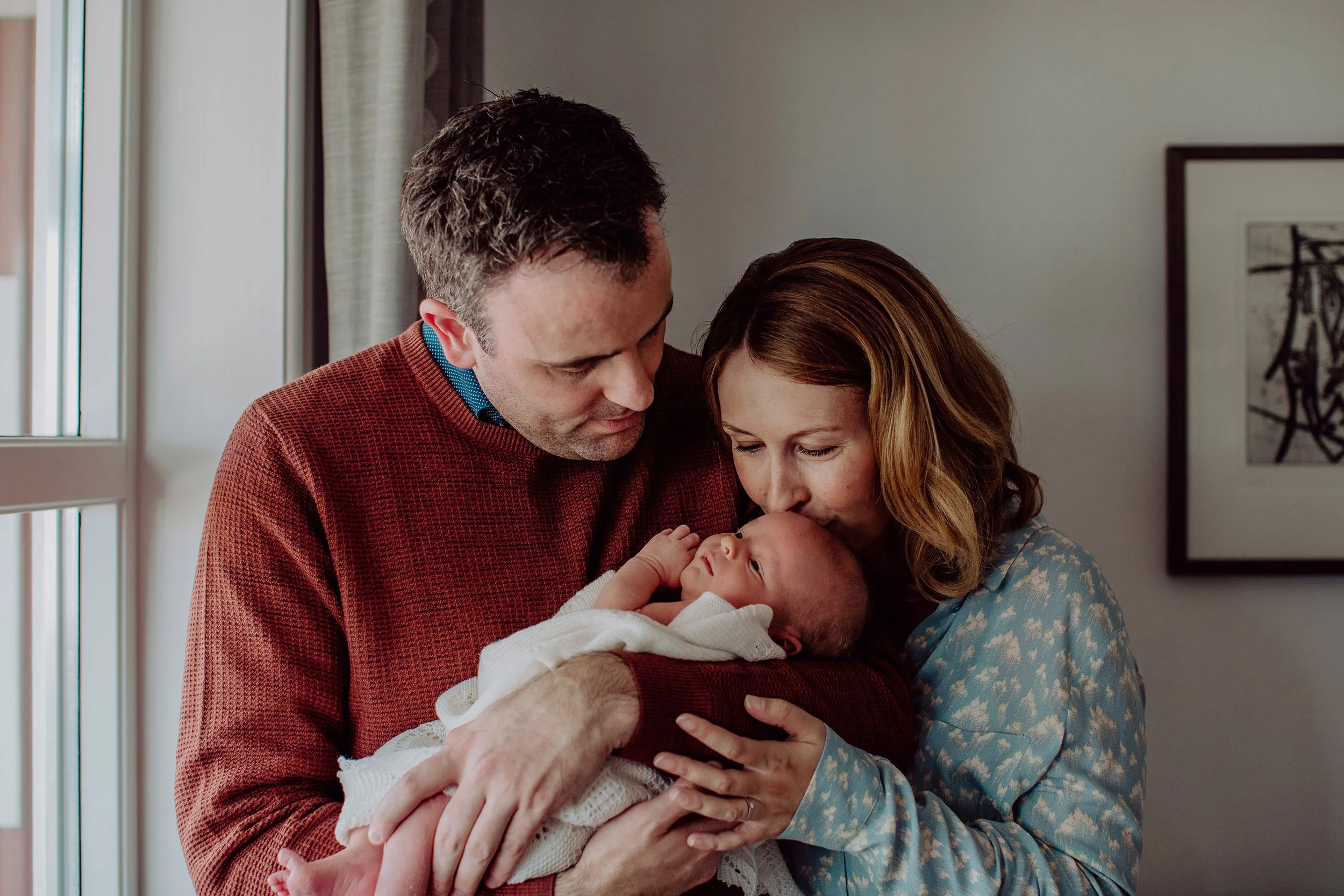 Nyfødtfotografering. Mor og far holder baby i armene.