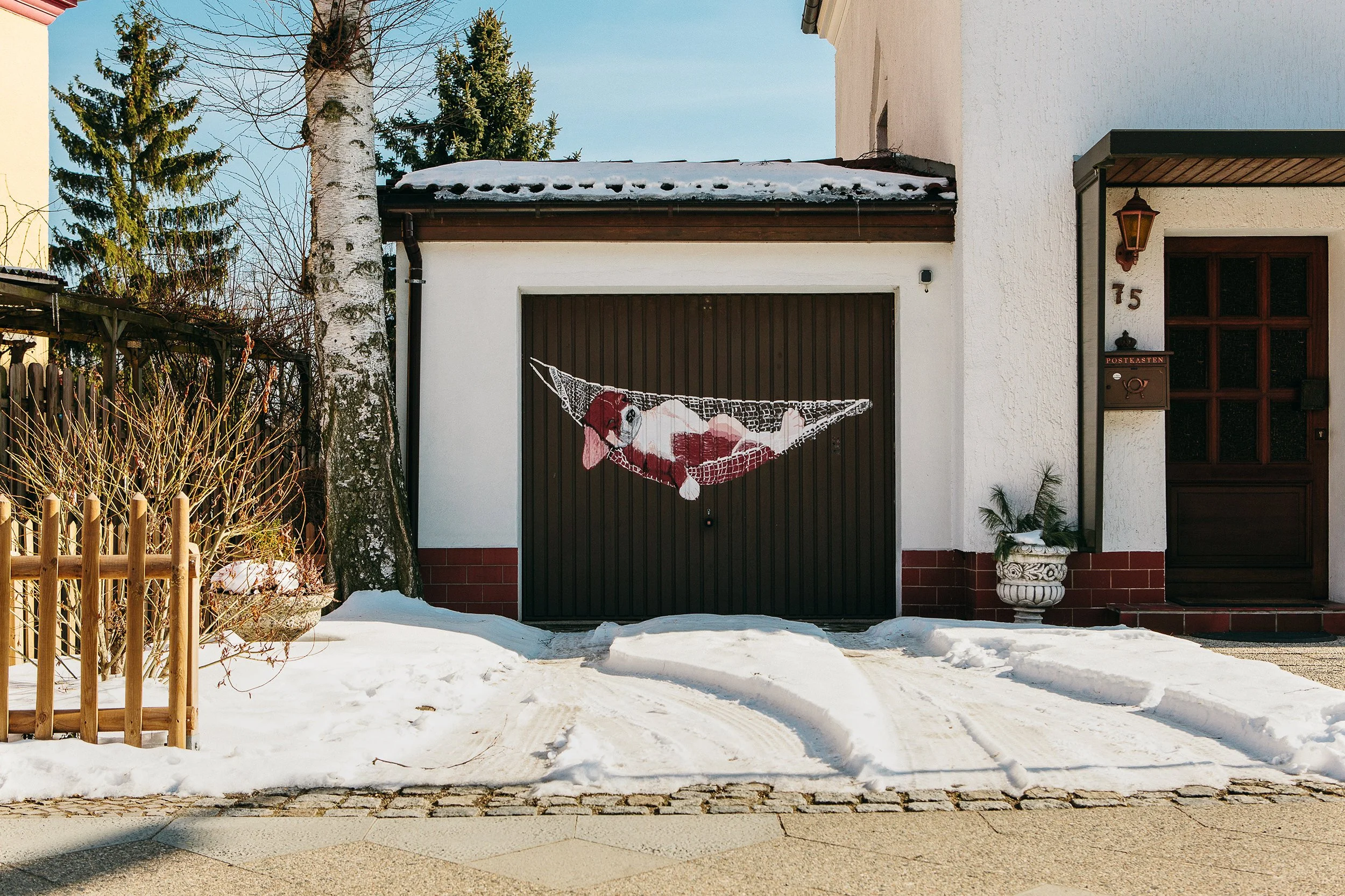 Garasjeport med veggmaleri av en hund som sover i en hengekøye.