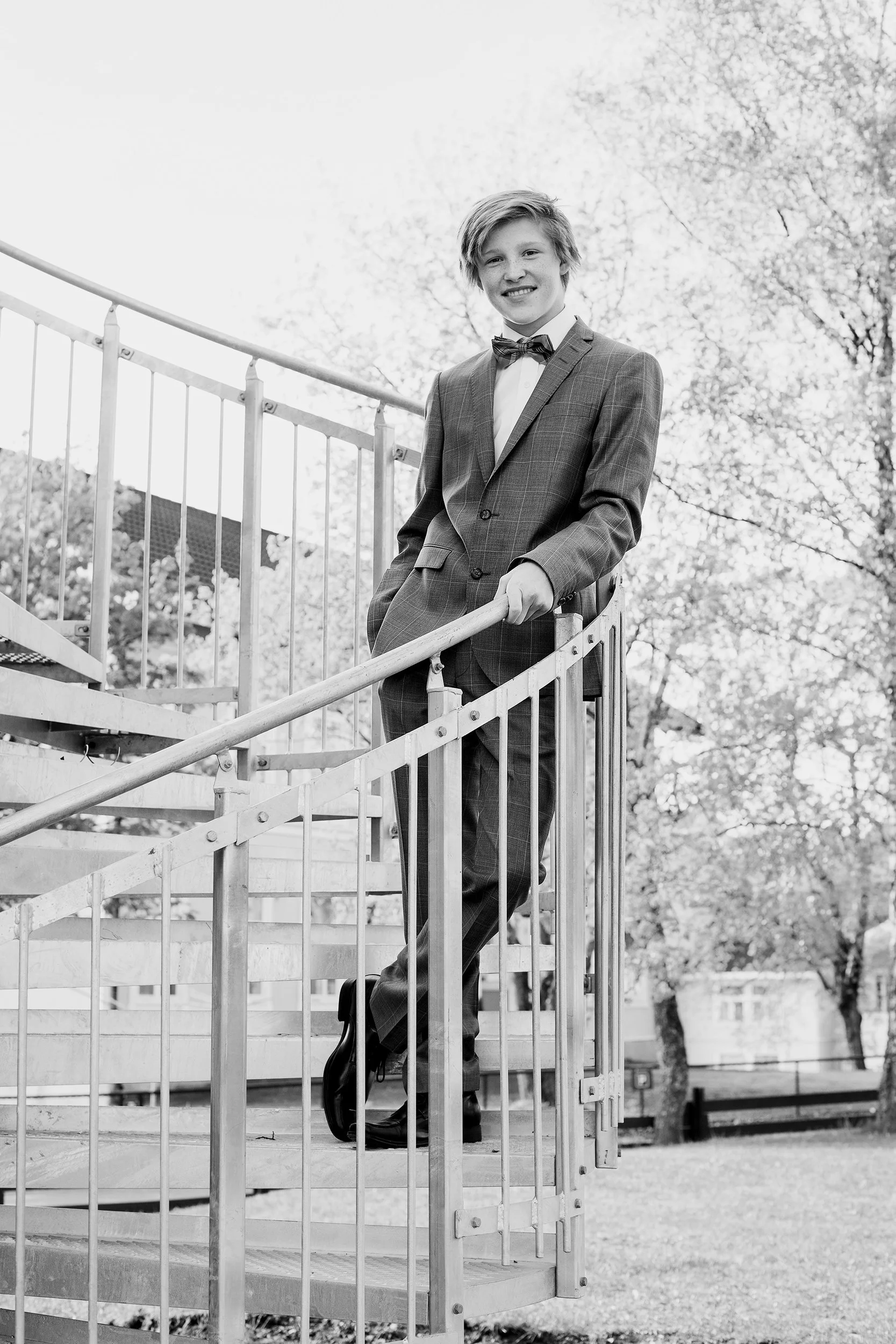 Konfirmantfotografering av gutt stående i en vindeltrapp med dress