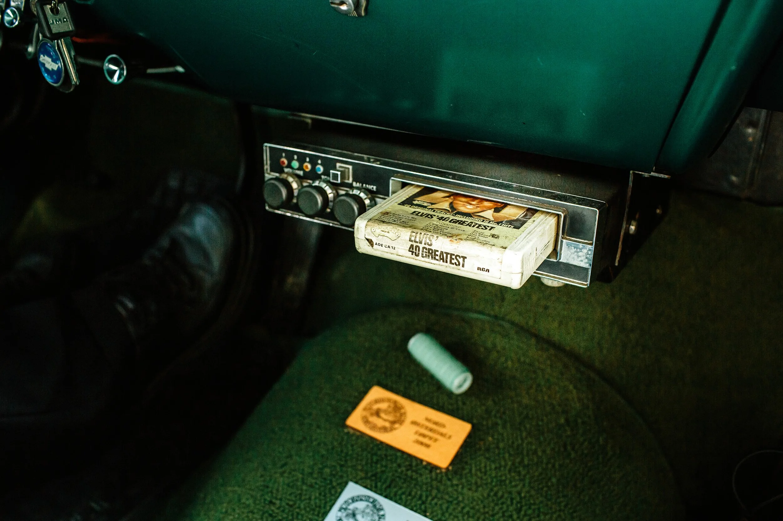 Kassett med Elvis´ 40 beste hits i kassettspilleren i en gammel veteranbil med grønt interiør.
