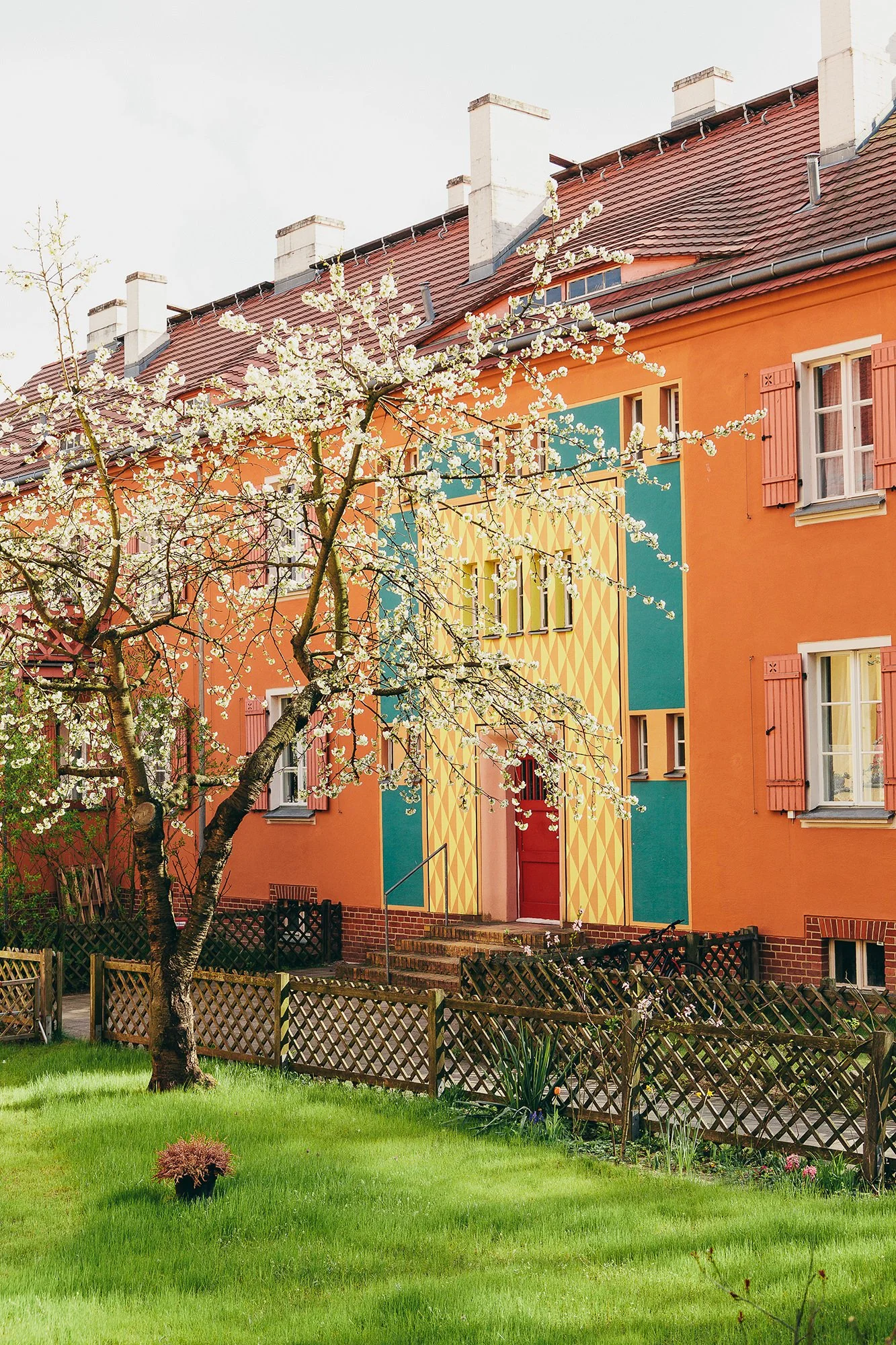 Orange boligblokk med fargerikt utsmykket inngangsparti i boligfeltet Gartenstadt Falkenberg i Berlin.