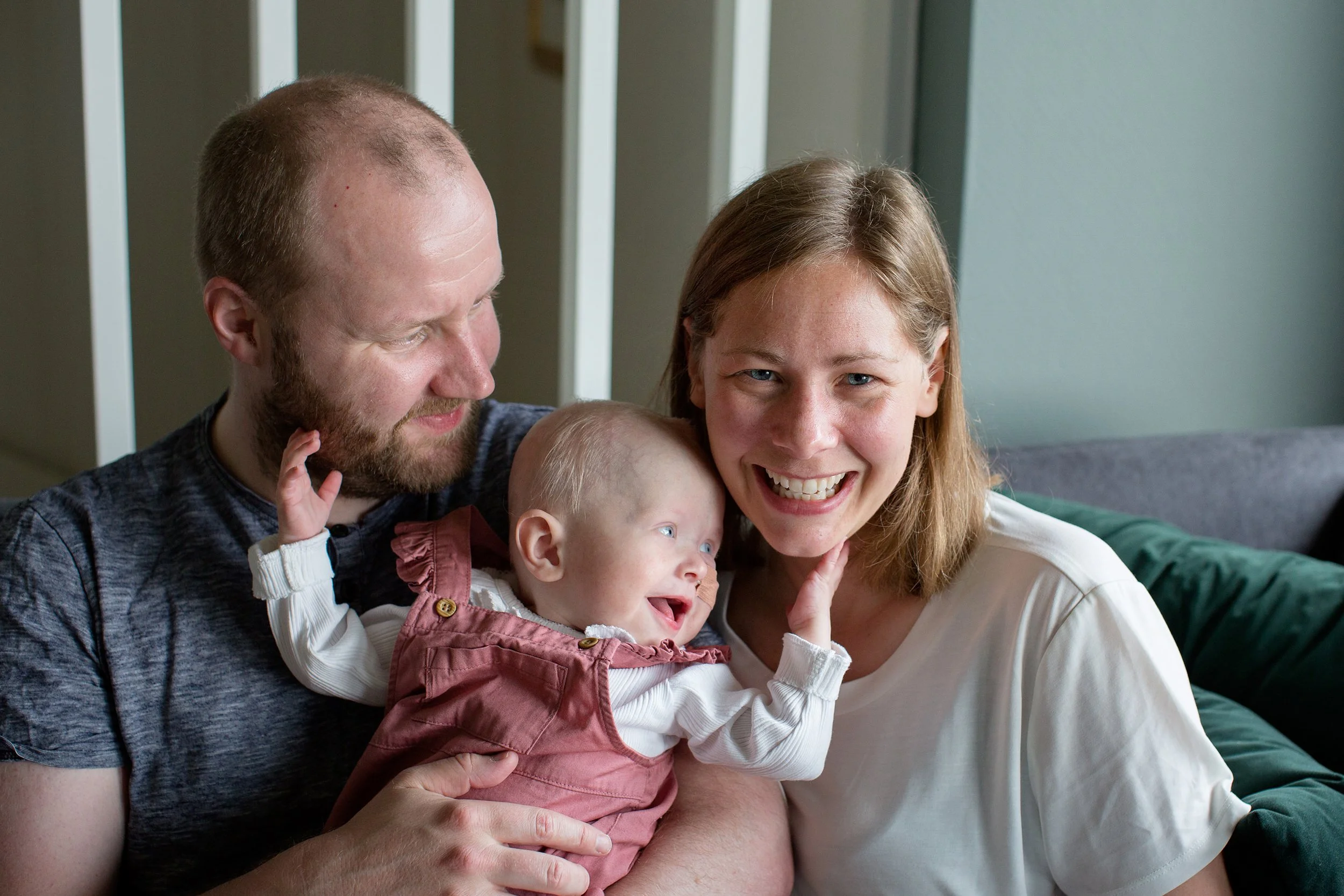 Familiefotografering i naturlig lys hjemme hos. Familie på tre med far, mor og baby.