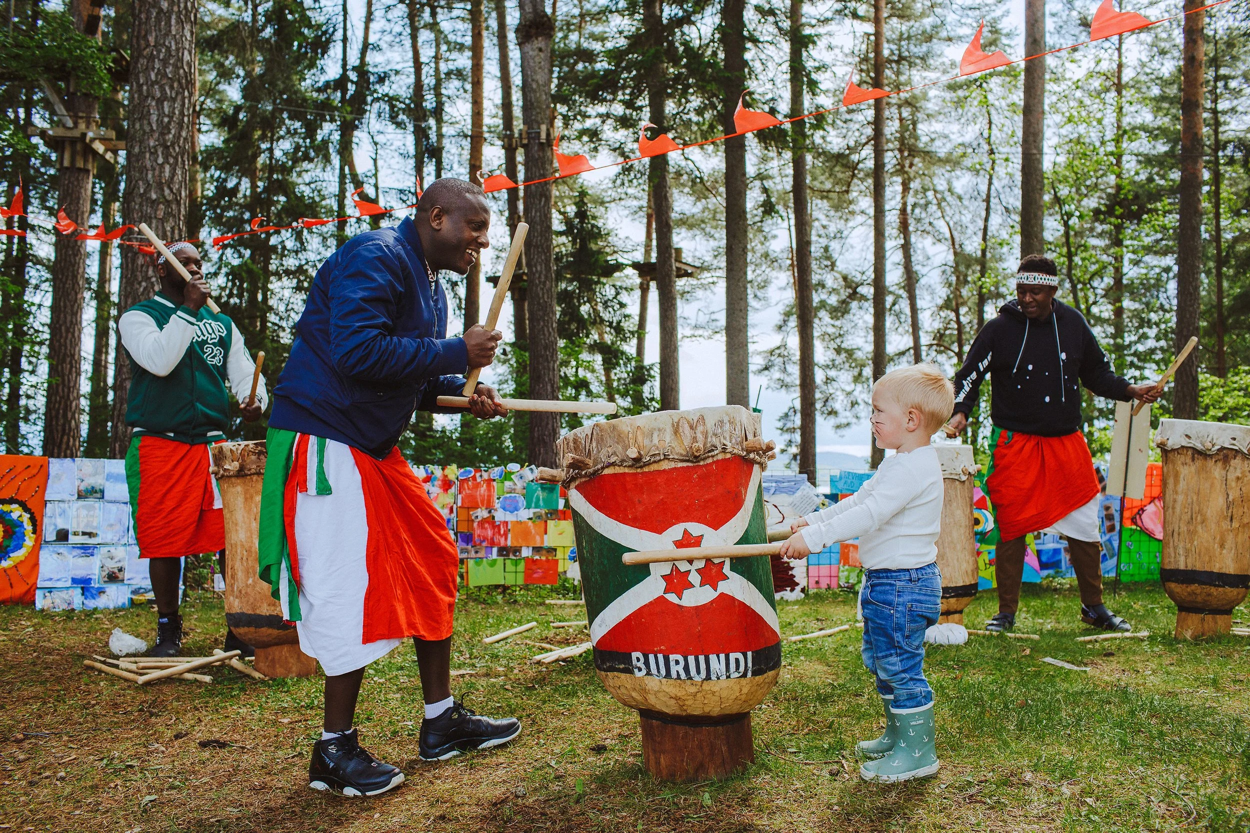 Stoppested Verden internasjonal barnefestival. Liten gutt spiller trommer sammen med artister.