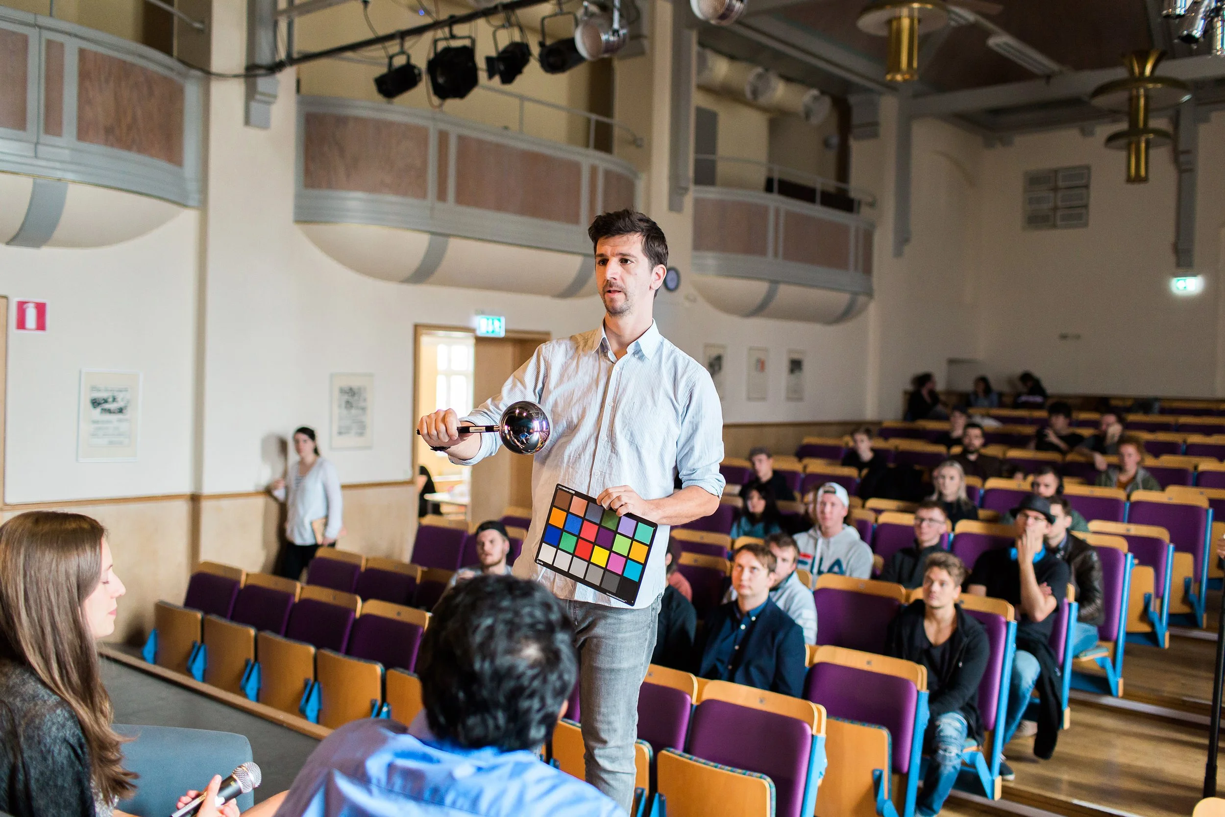 Lærer på filmskole hjelper elever å ta lydprøver og fargeprøver med en kromball og fargekart.