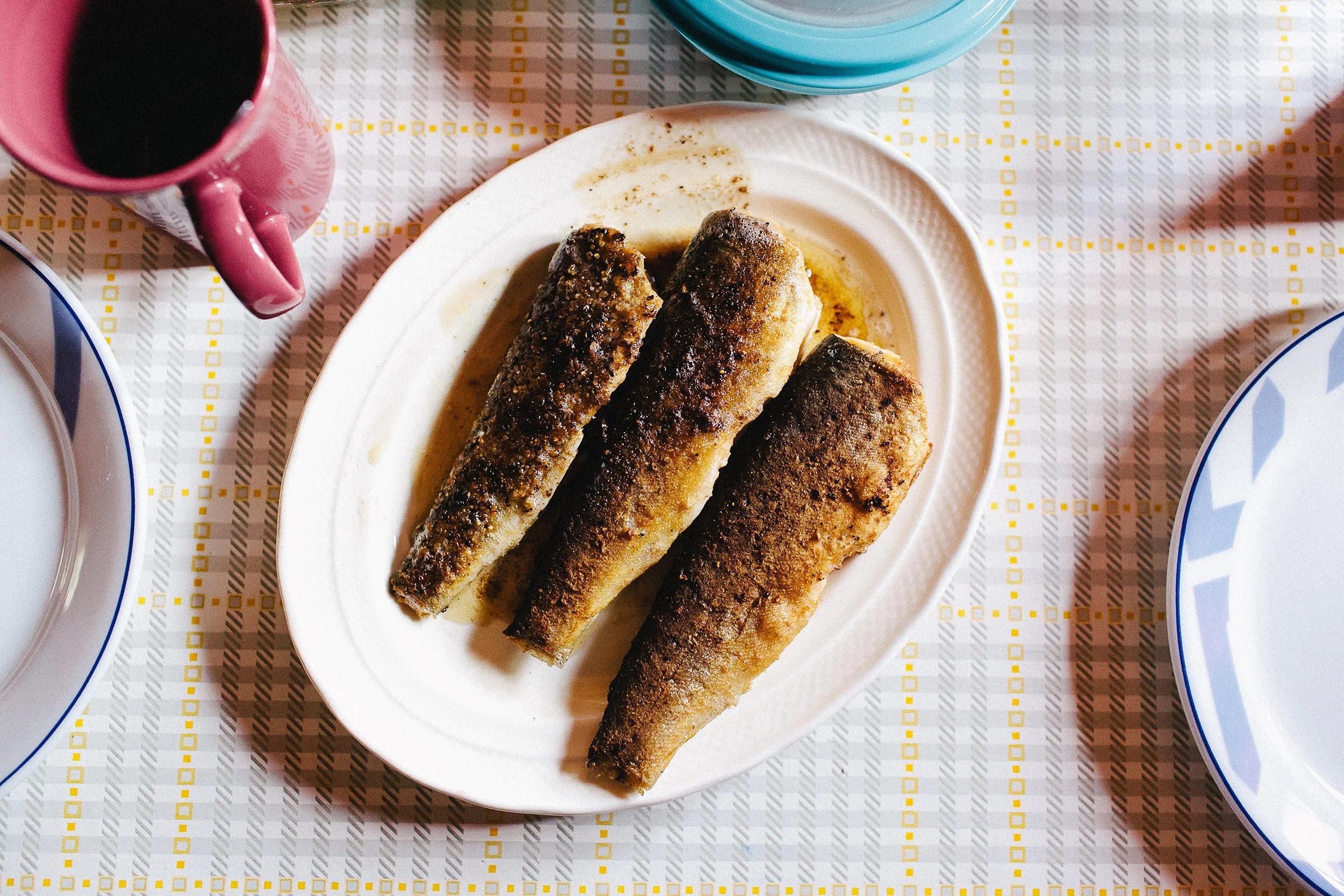 Tre stekte fiskestykker på et fat fotografert i fugleperspektiv.