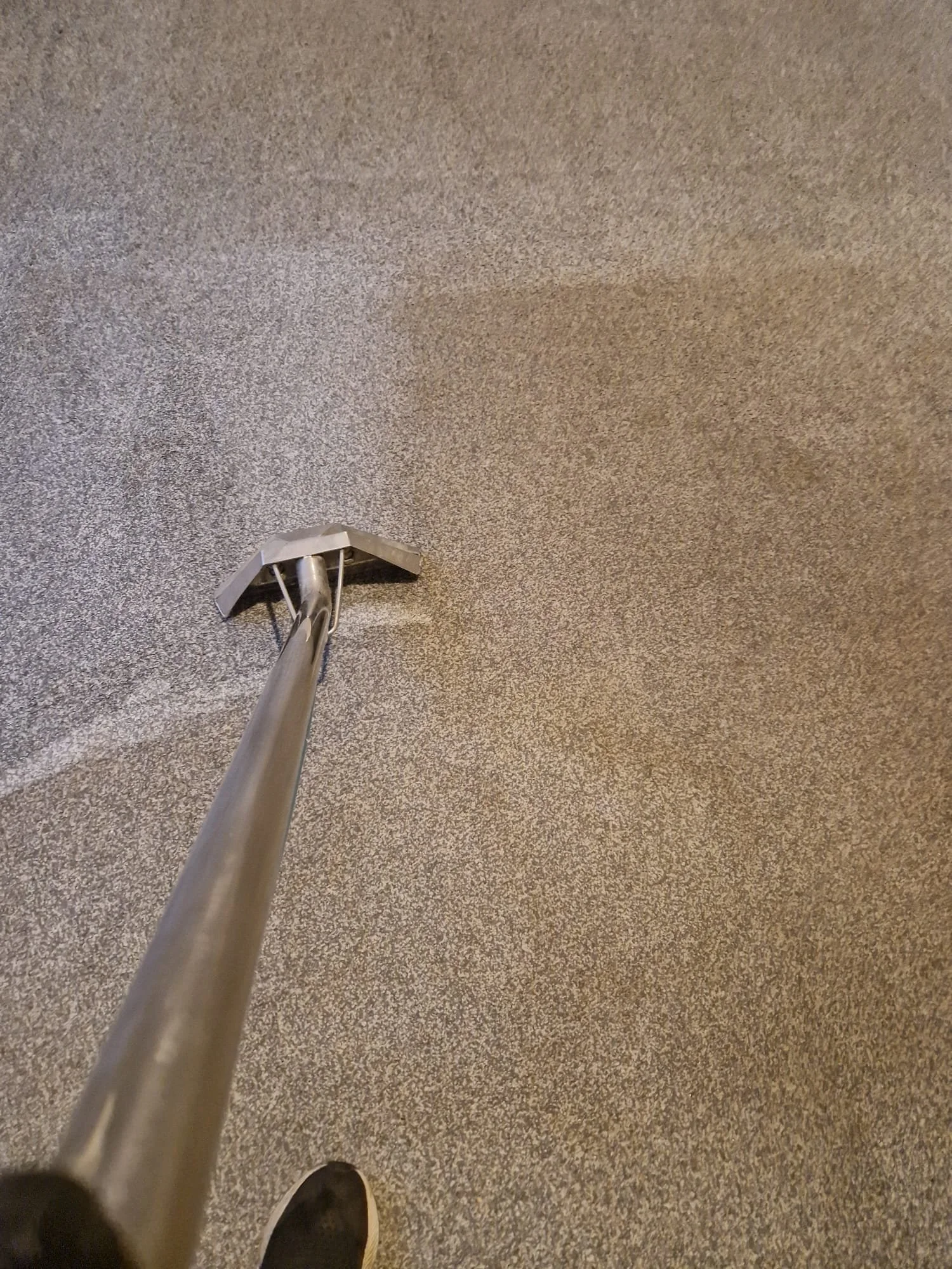 View of the ceiling with a ceiling cleaning tool attached to a telescoping pole. A shoe is visible at the bottom of the image.