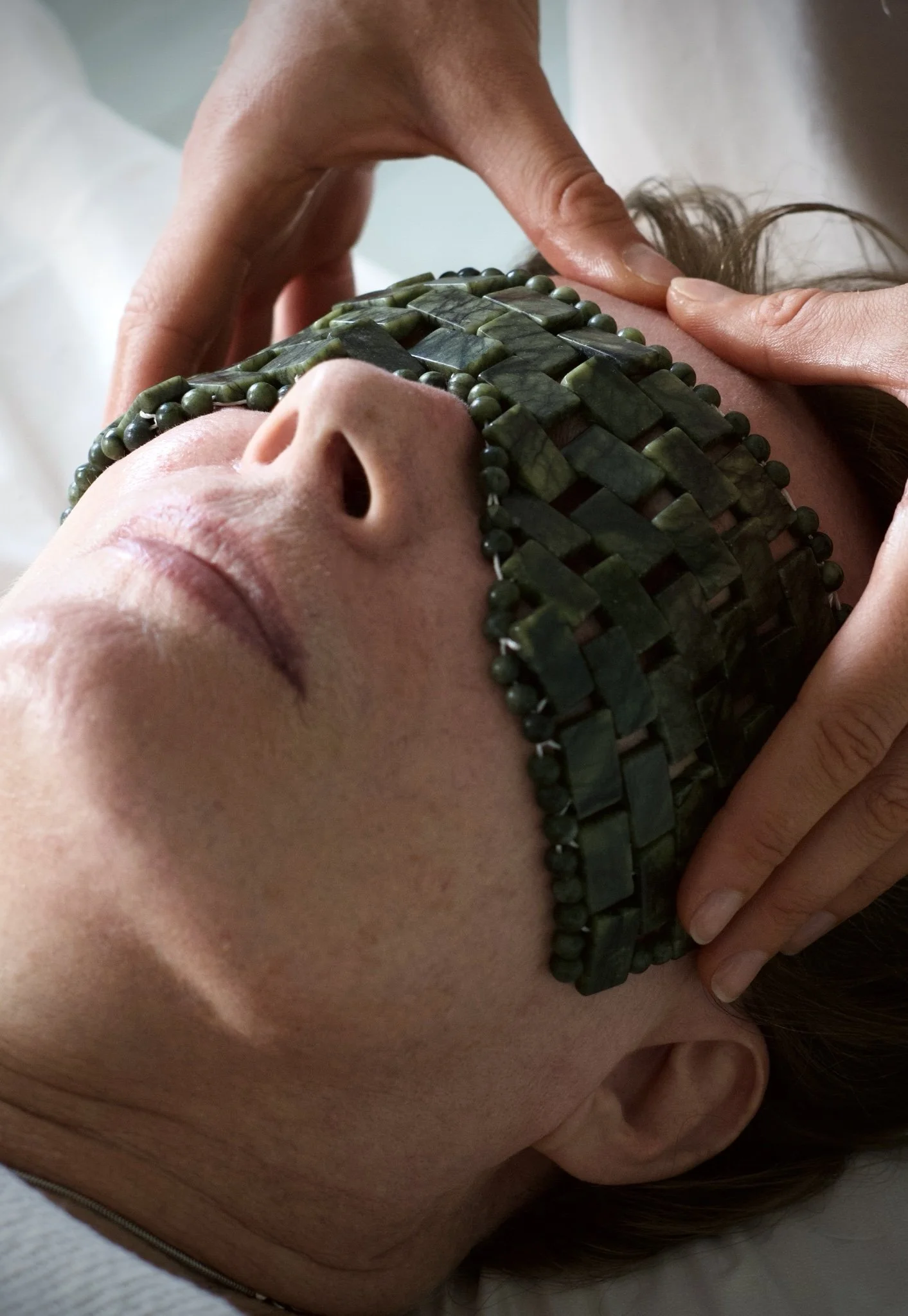 Person receiving a facial massage while wearing a beaded eye mask.