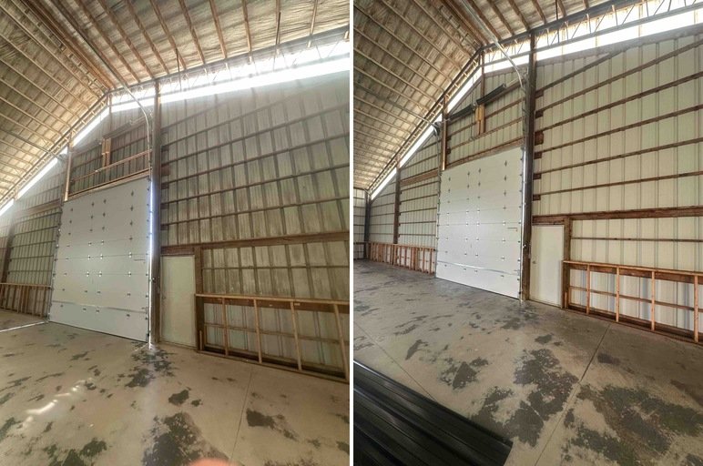Inside an empty industrial warehouse with a high curved ceiling, large white garage door, and unfinished walls.