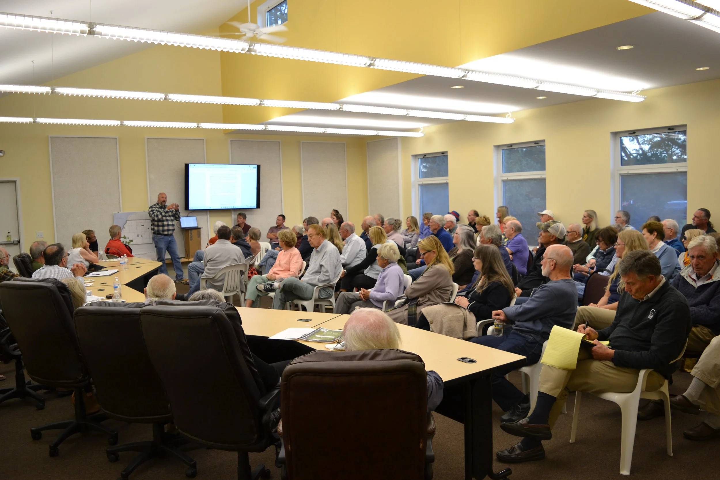 Attendees are shown listening to a presentation.