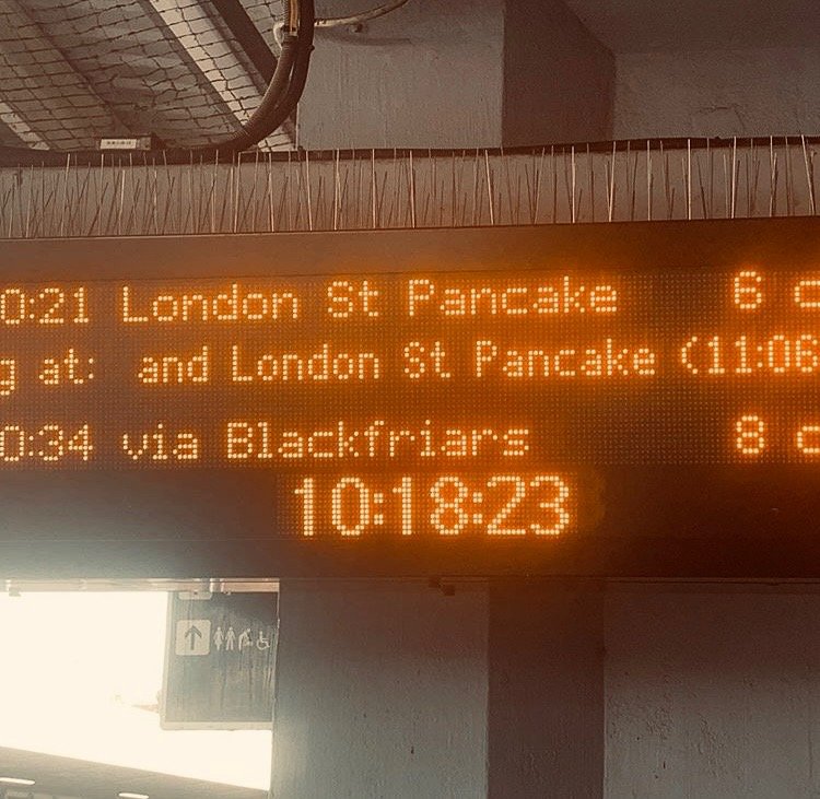 Electronic bus schedule display showing departure times and routes, including London St Pancake, Blackfriars, and the current time 10:18:23.