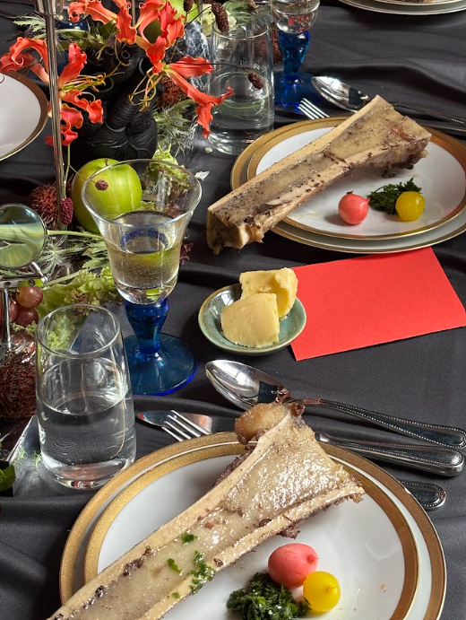 Surrealistic dining table set up. A big bone marrow on a golden plate.