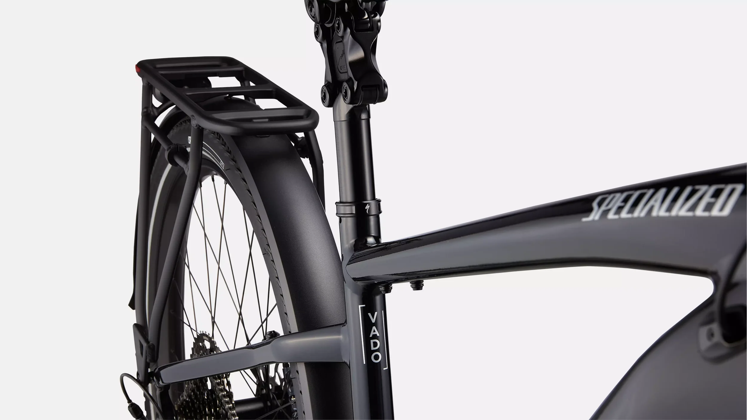 Close-up van een zwart Specialized Vado elektrische fiets, zichtbaar vanaf de achterzijde met een bagagedrager en de achterkant van het frame.