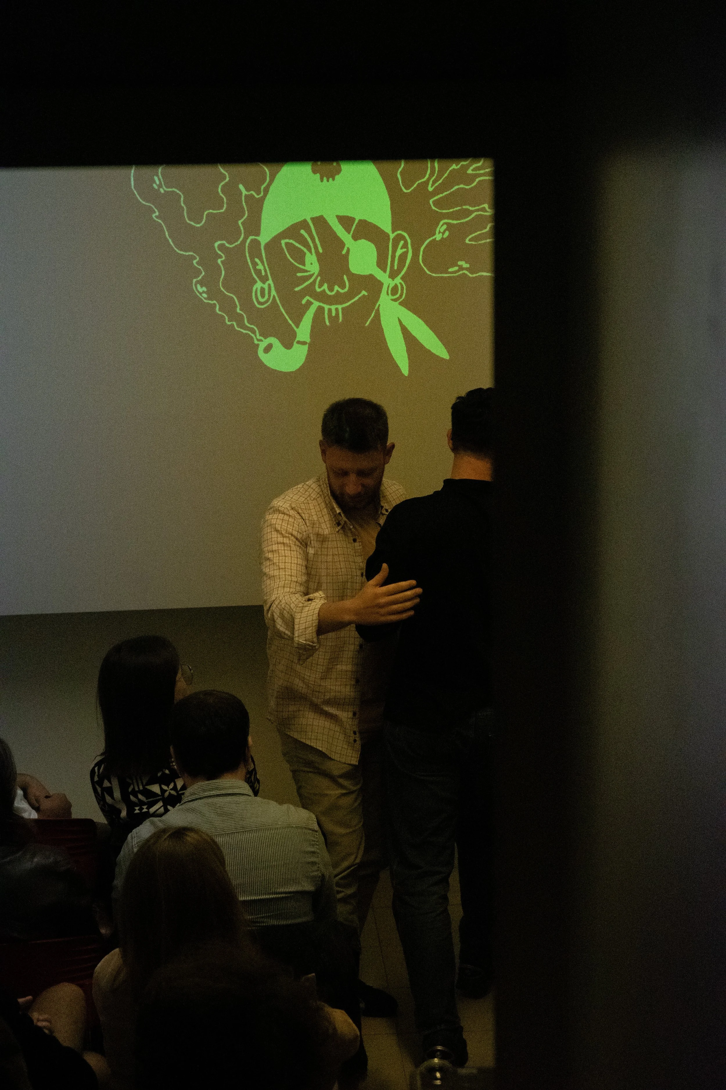 People gathered in a dark room watching a cartoon pirate face projection on the wall.