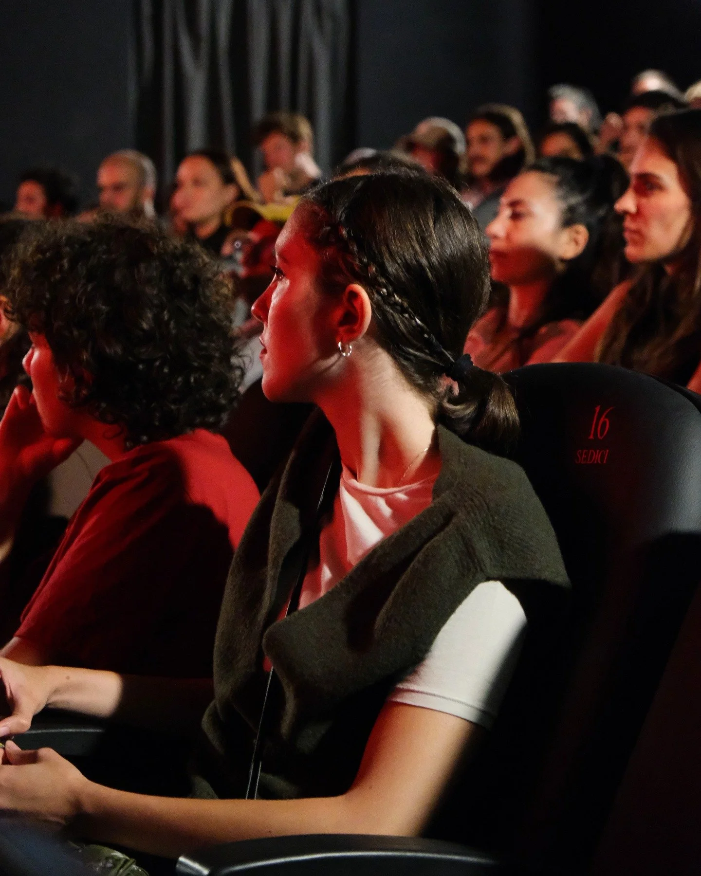 Audience members sitting in theater seats, attentively watching a performance or presentation.