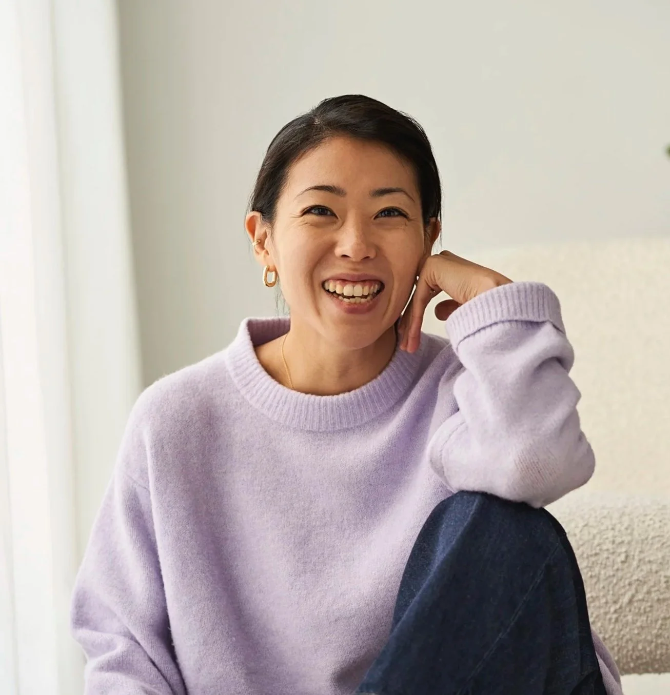 Lächelnde Frau in lila Pullover sitzend im Wohnzimmer