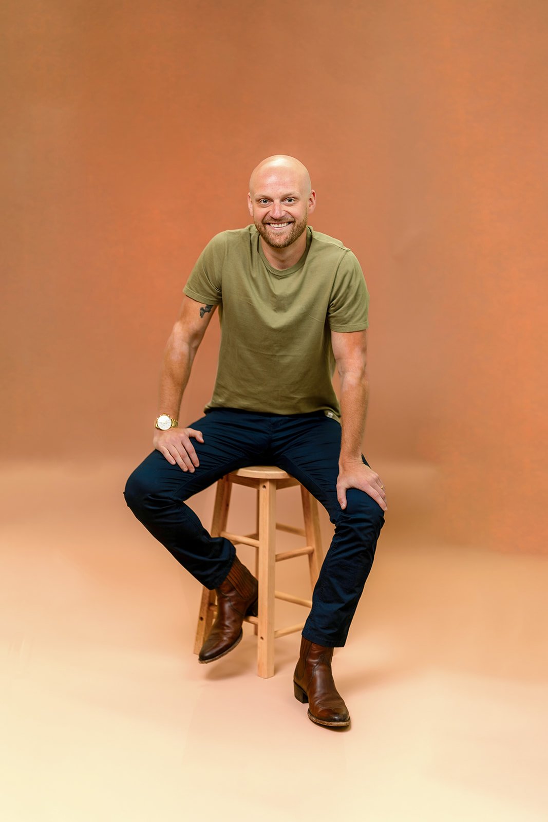 photo of a young man posing on a stool smiling for a photo