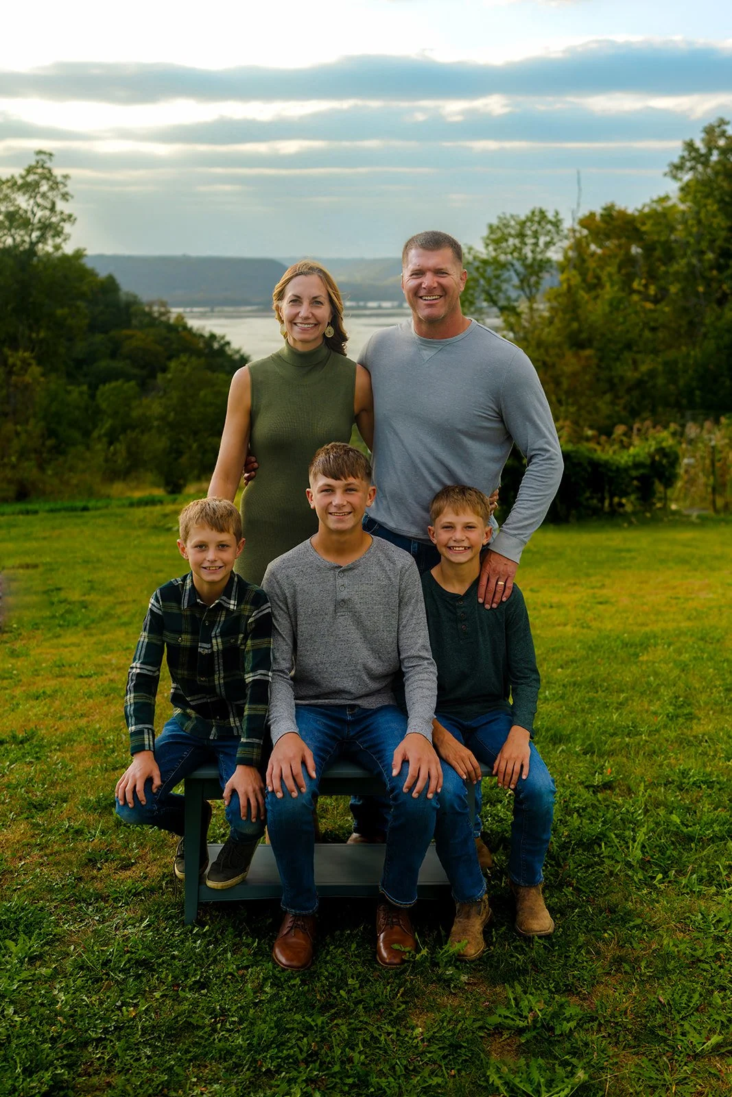three kids and two parents smile for a family photo in their backyard