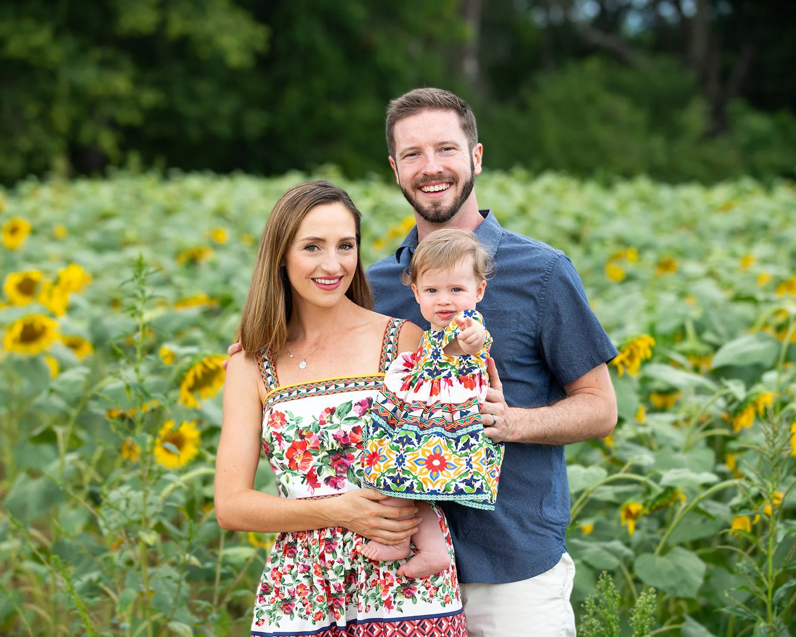 a family of three pose in a sunflower garden