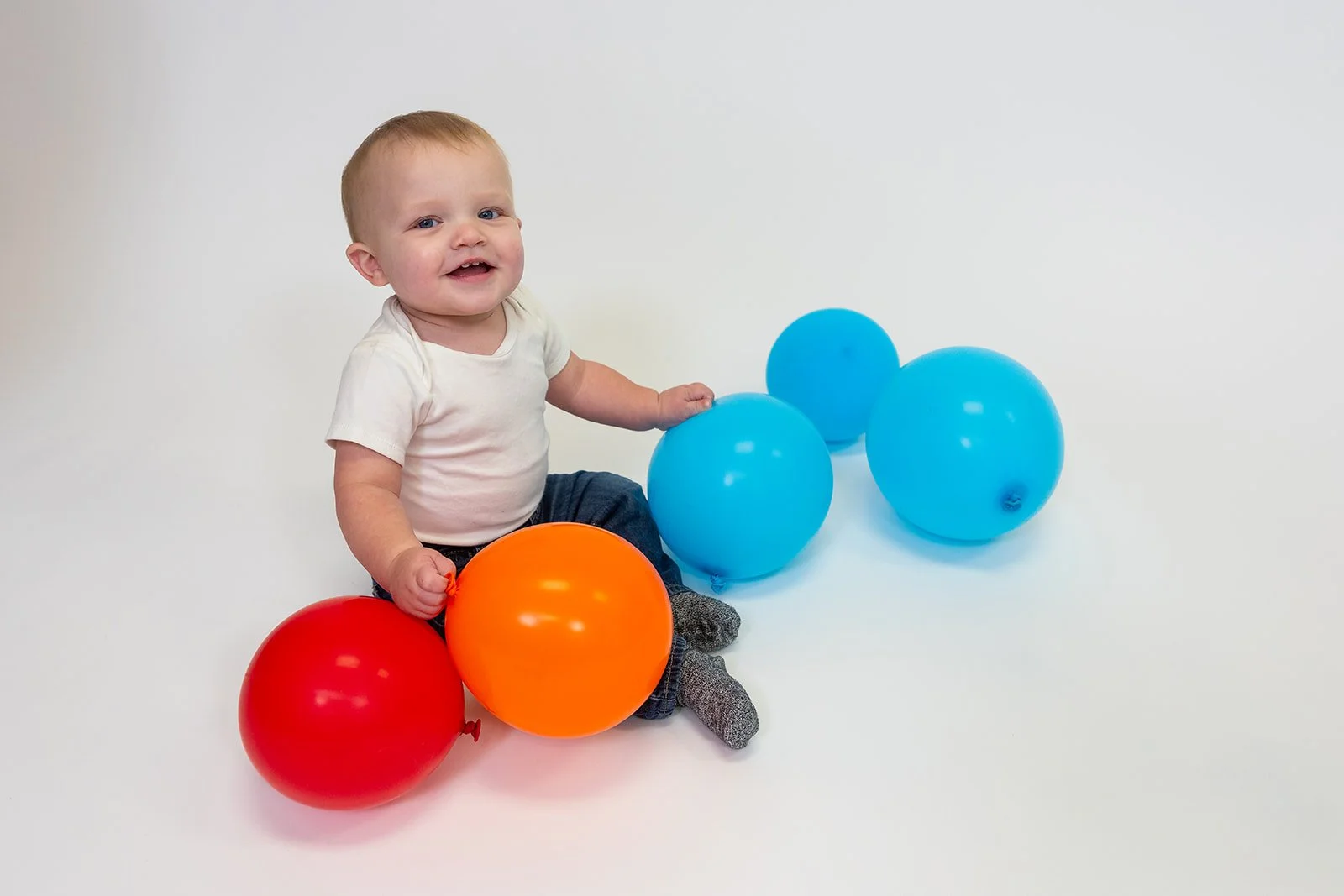a one year old poses with balloons for a portrait
