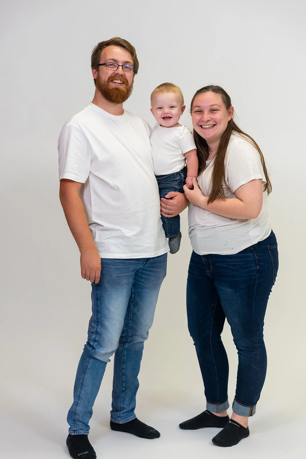 a young family smiles at the park for a family photo