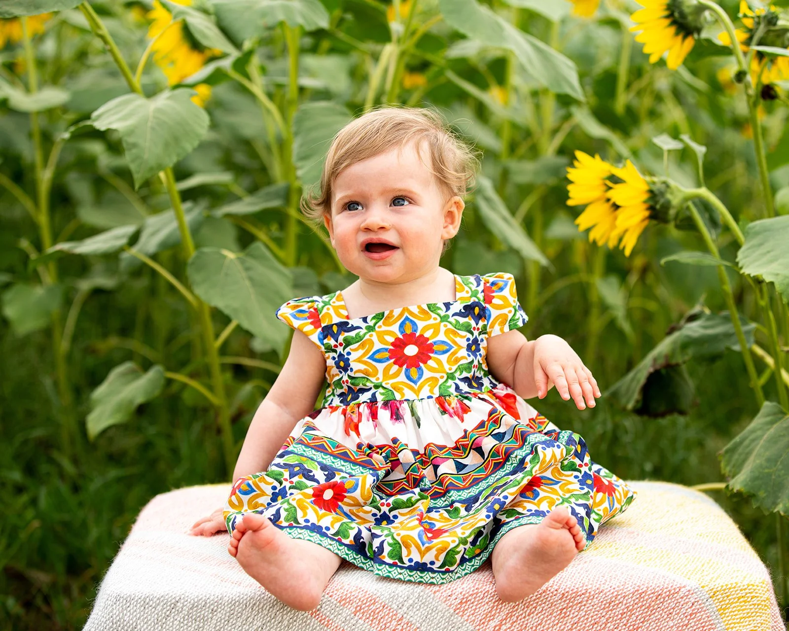 a little girl smiles in a sunflower garden