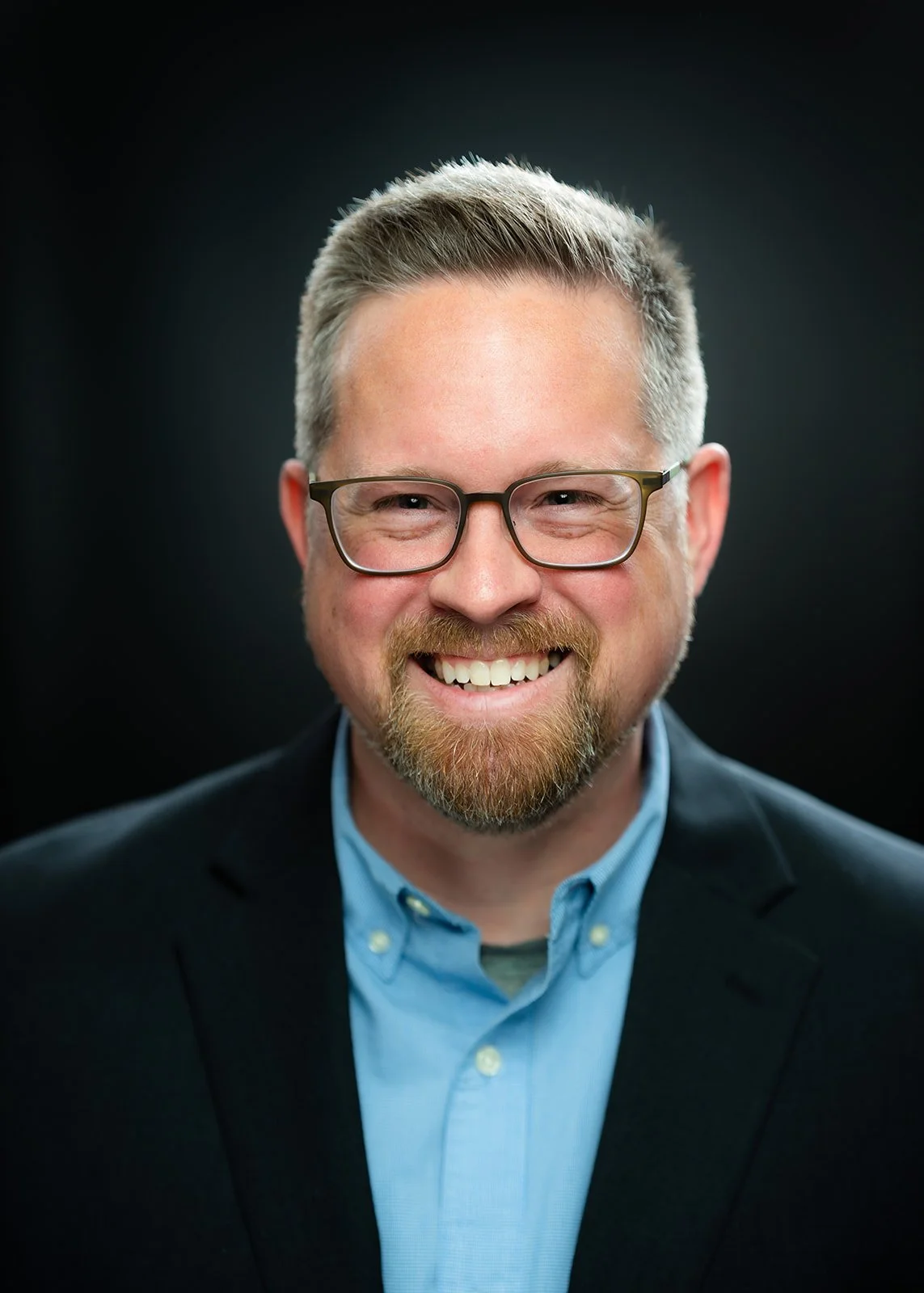 photo of a smiling businessman posing for a studio headshot