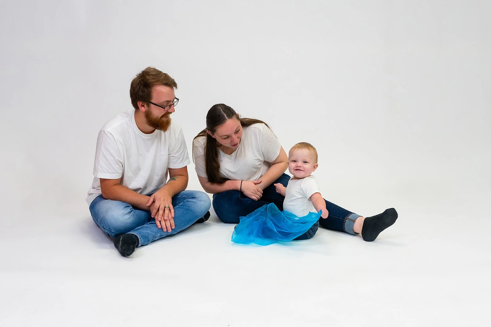 two parents and one boy smile together in a studio portrait