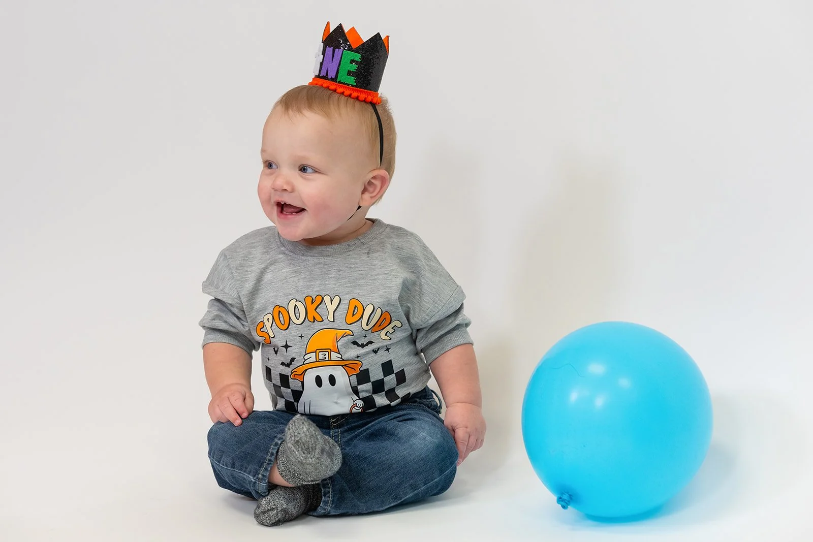 a little boy smiles next to a balloon