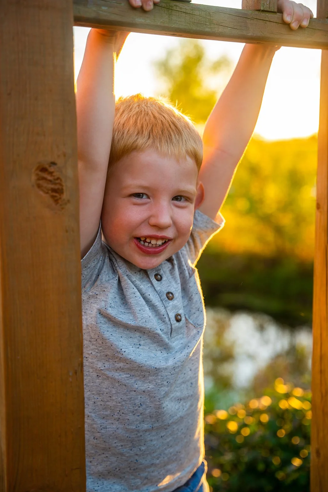 A boy hangs from a post smiling