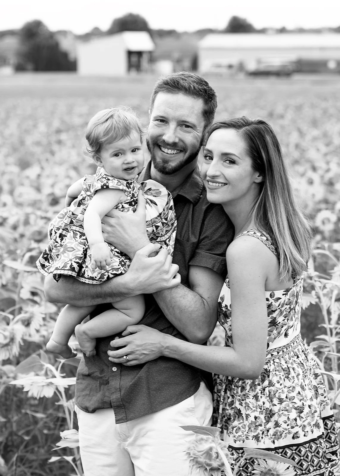 a family of three pose in a sunflower garden