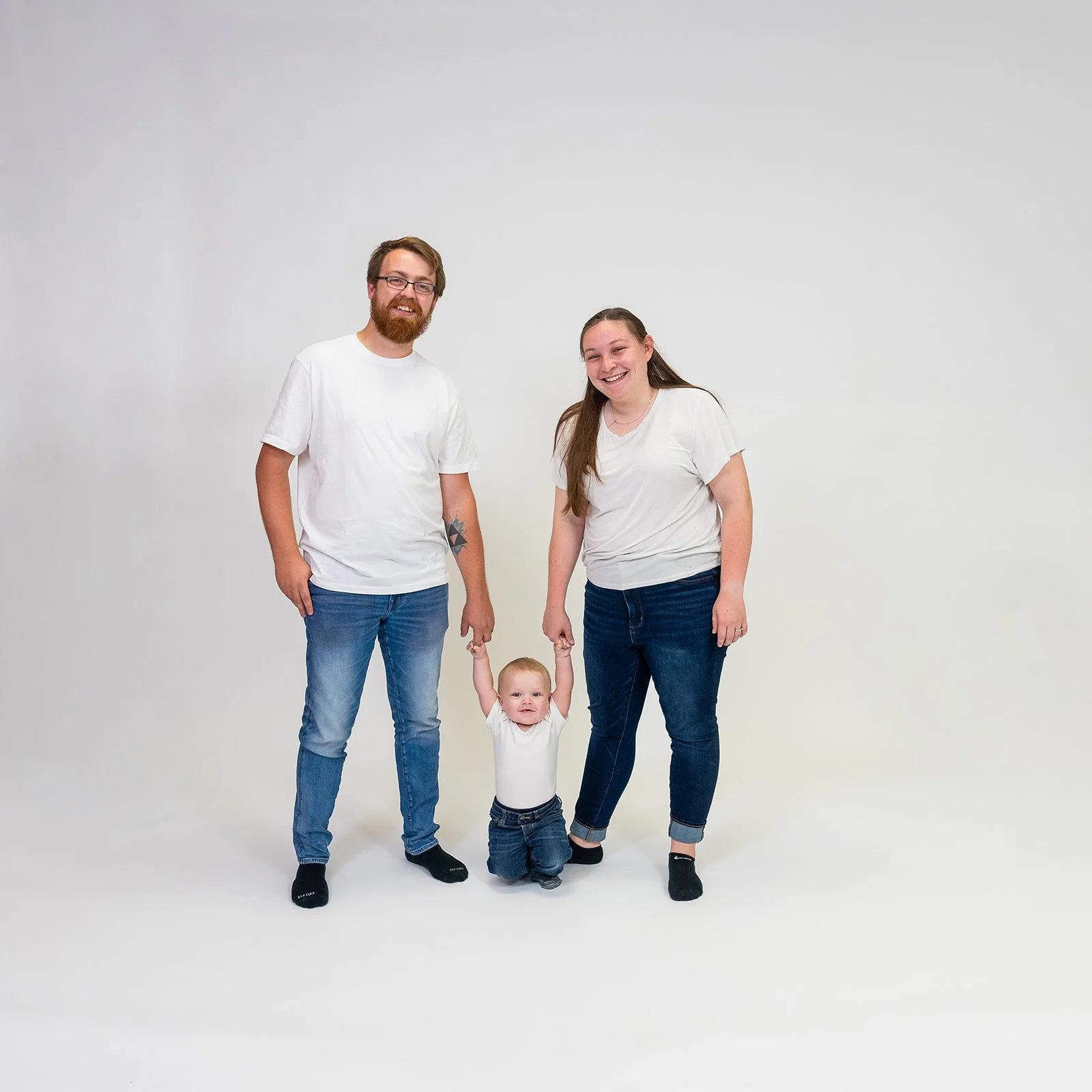 a family of three poses for a studio photoshoot wearing all white