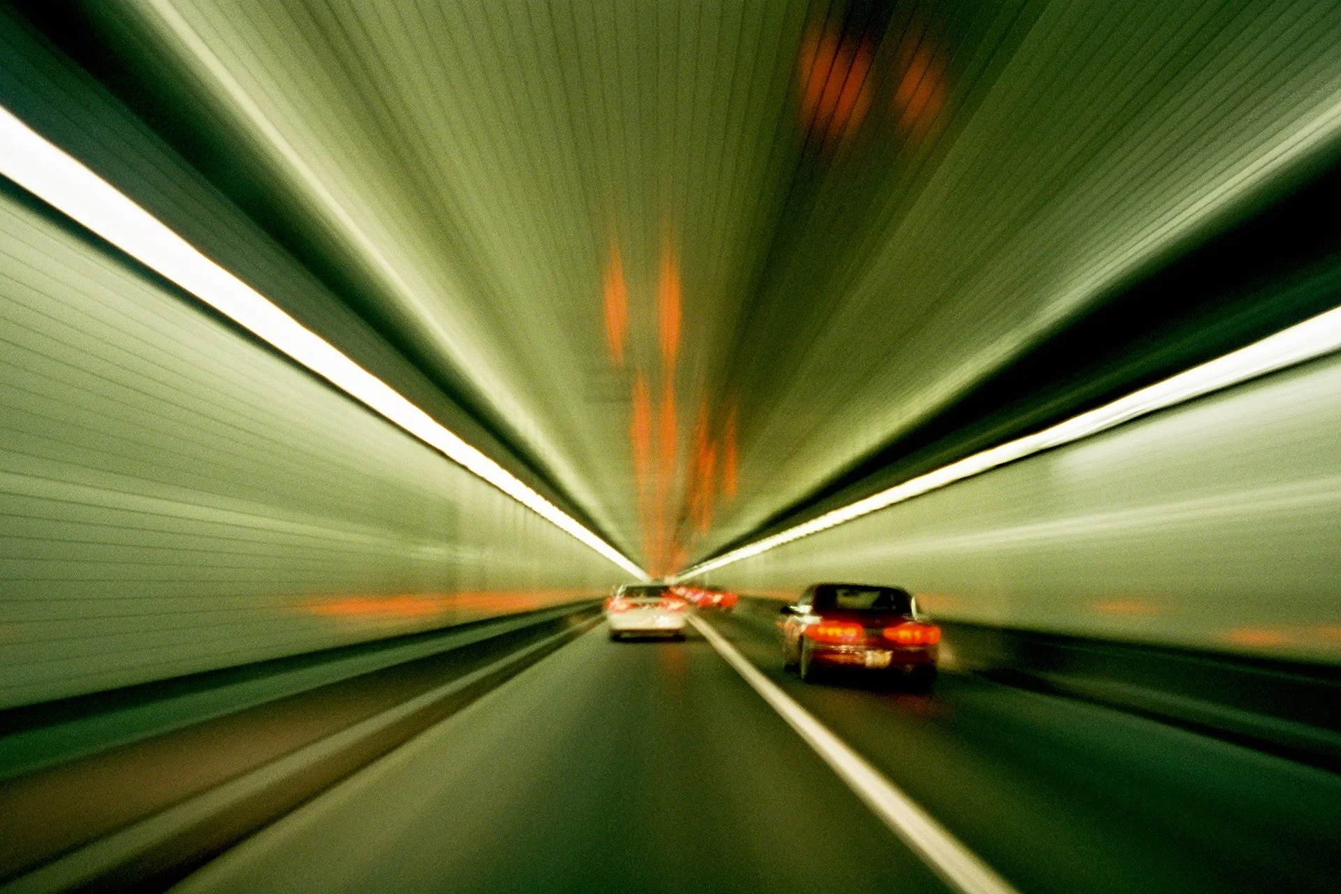 Cars driving through a tunnel with light streaks creating a motion blur effect.