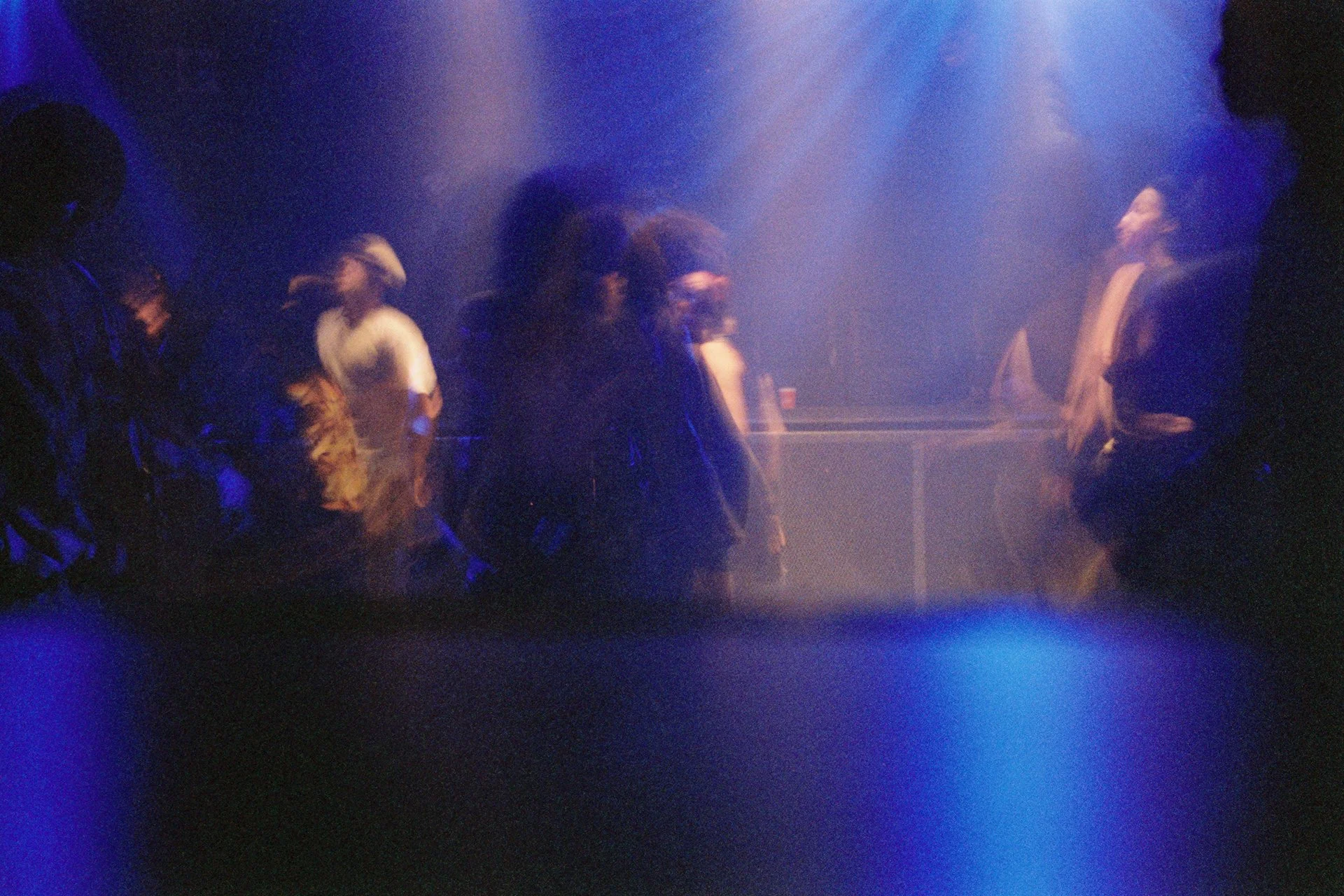 People standing in a line in a dimly lit, smoky atmosphere with blue lighting.