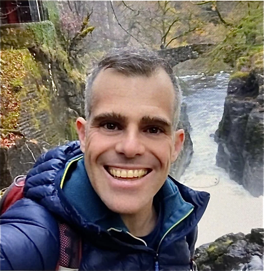 A man posing for the camera in front of a waterfall