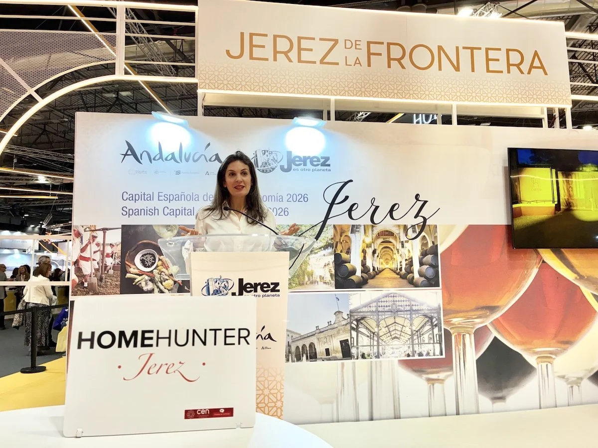 A woman at a booth at an exposition with a sign that reads Home Hunter Jerez