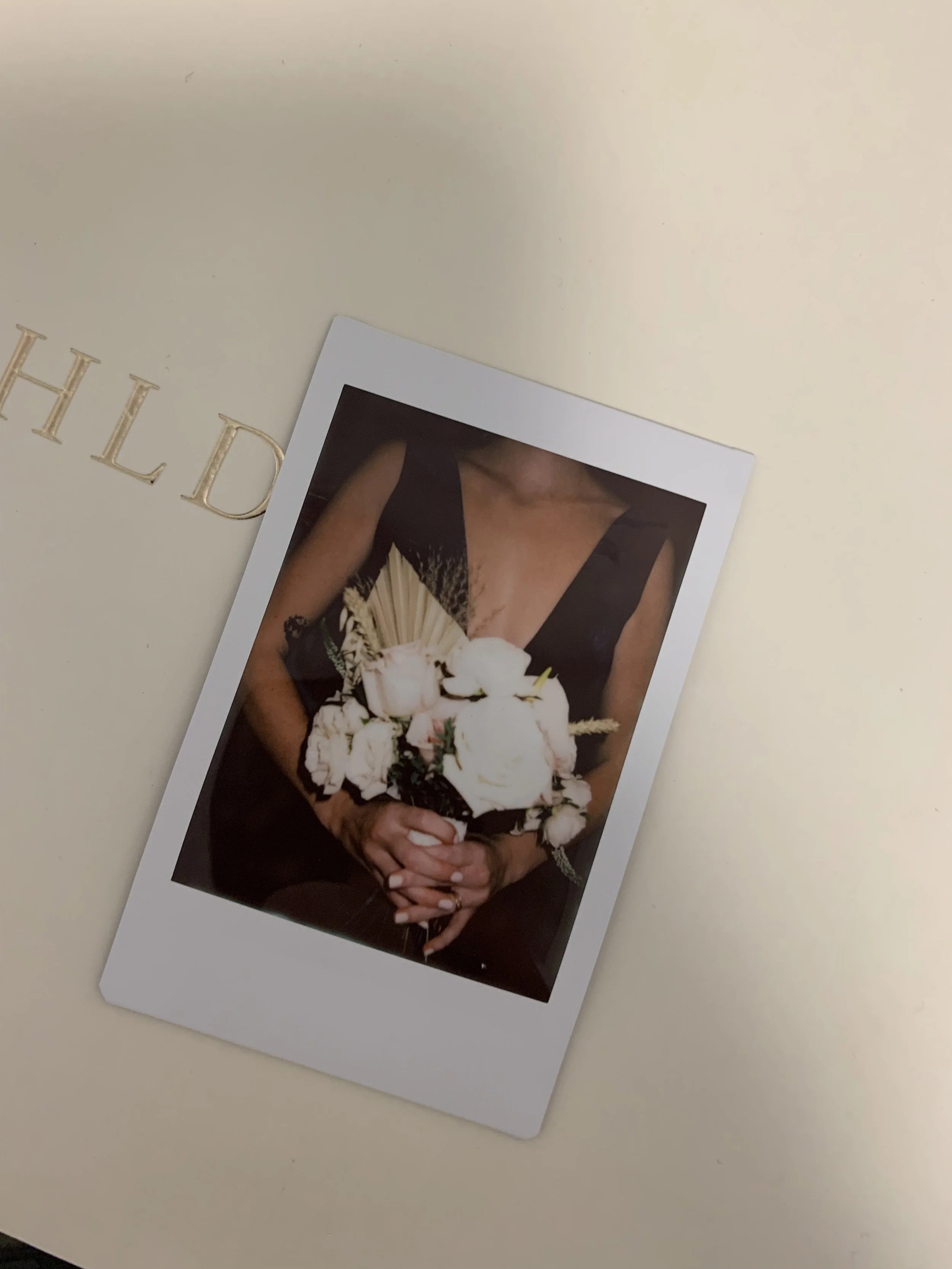 A person in a black dress holding a bouquet of white flowers.
