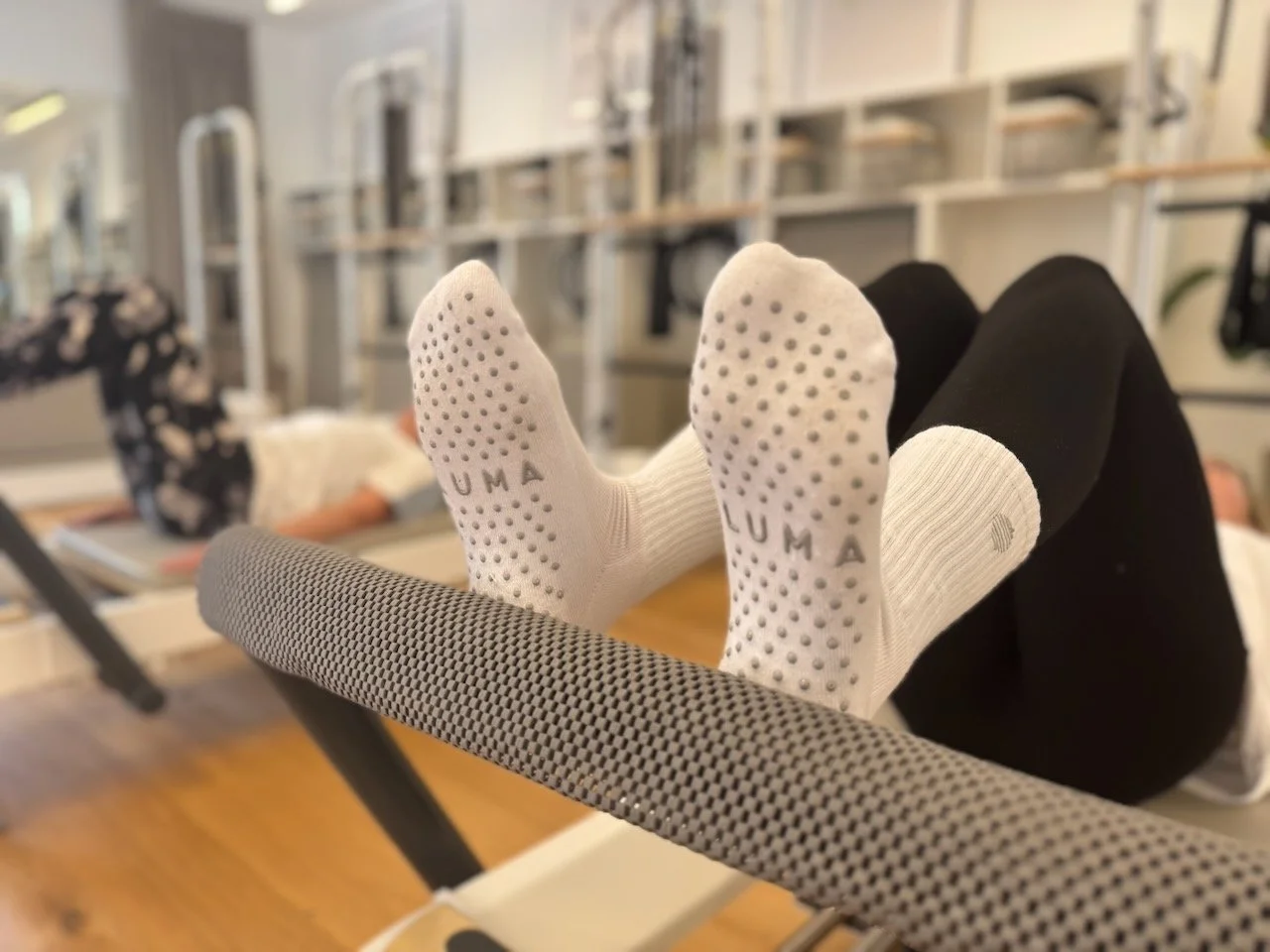 A client doing footwork on the Reformer wearing white crew grip socks at Luma Pilates, Edinburgh