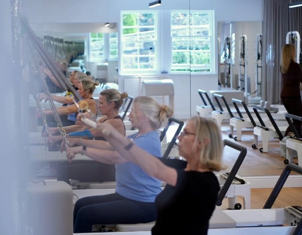 Clients doing seated lat pulldowns on a Reformer machines at Luma Pilates, Edinburgh